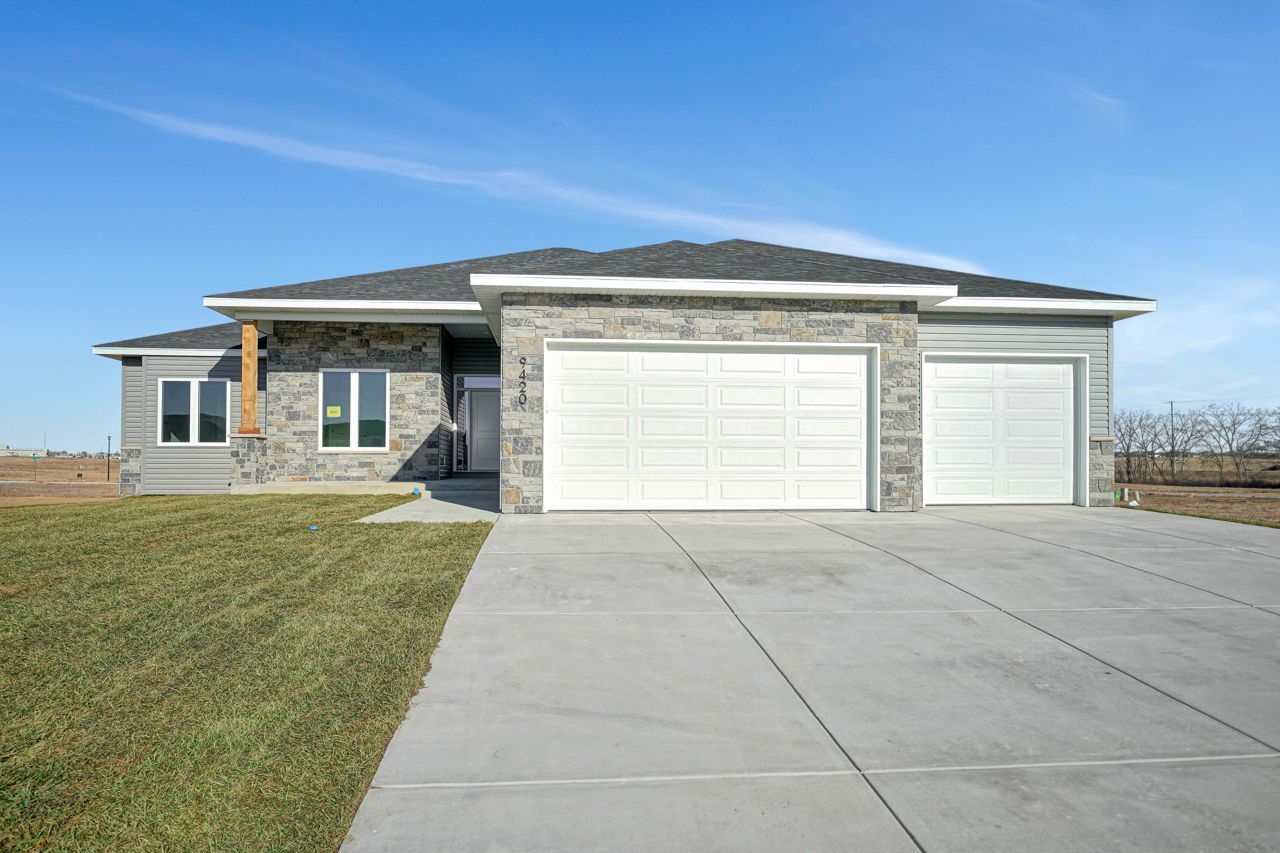 The front of a house with two garage doors and a concrete driveway.