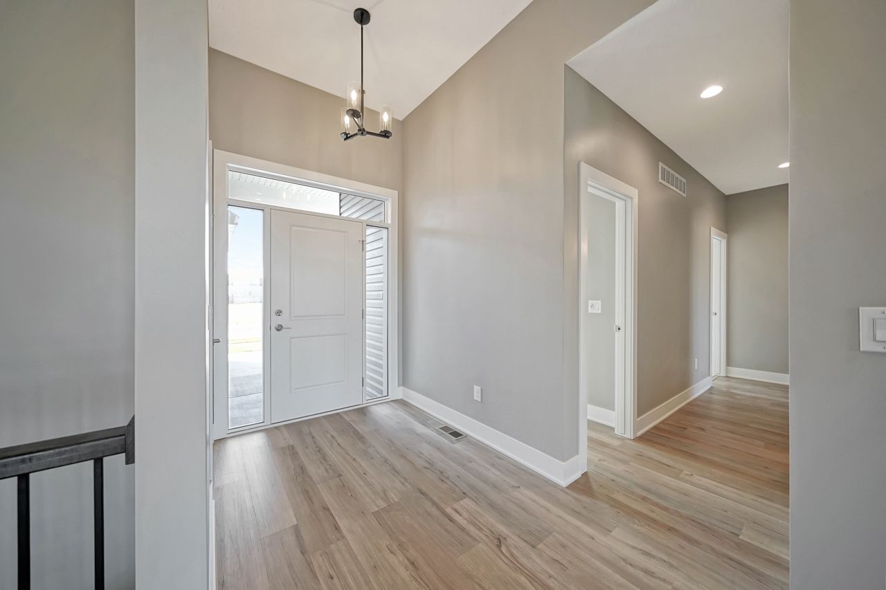 A hallway in a house with hardwood floors and a white door.