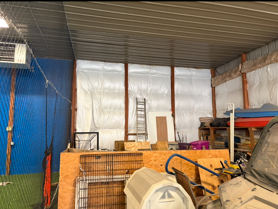 A garage filled with lots of junk and a ladder.