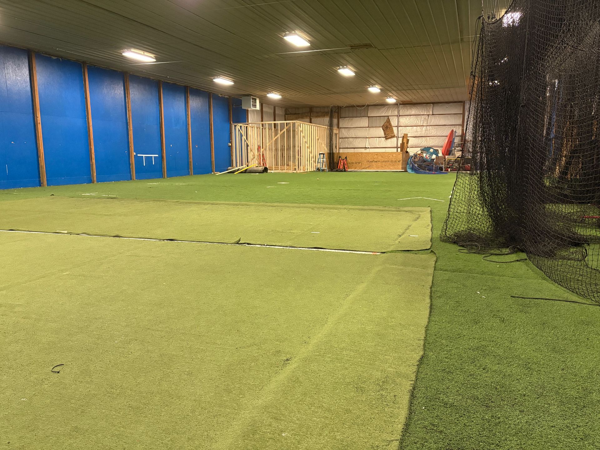 A large indoor stadium with a lot of grass and blue walls.