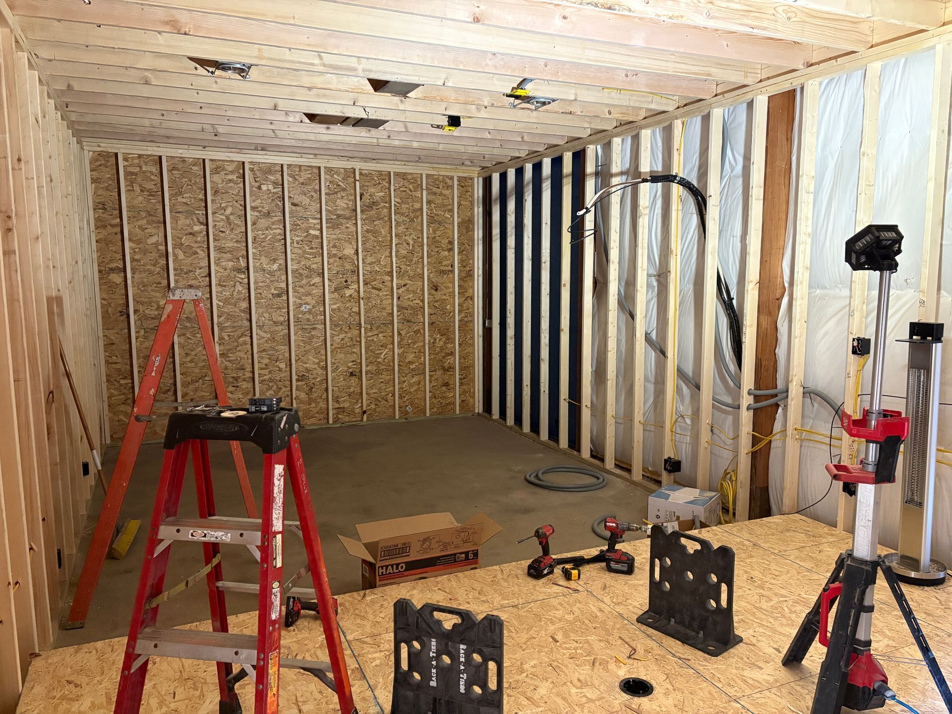 A room under construction with a ladder and tools on the floor.