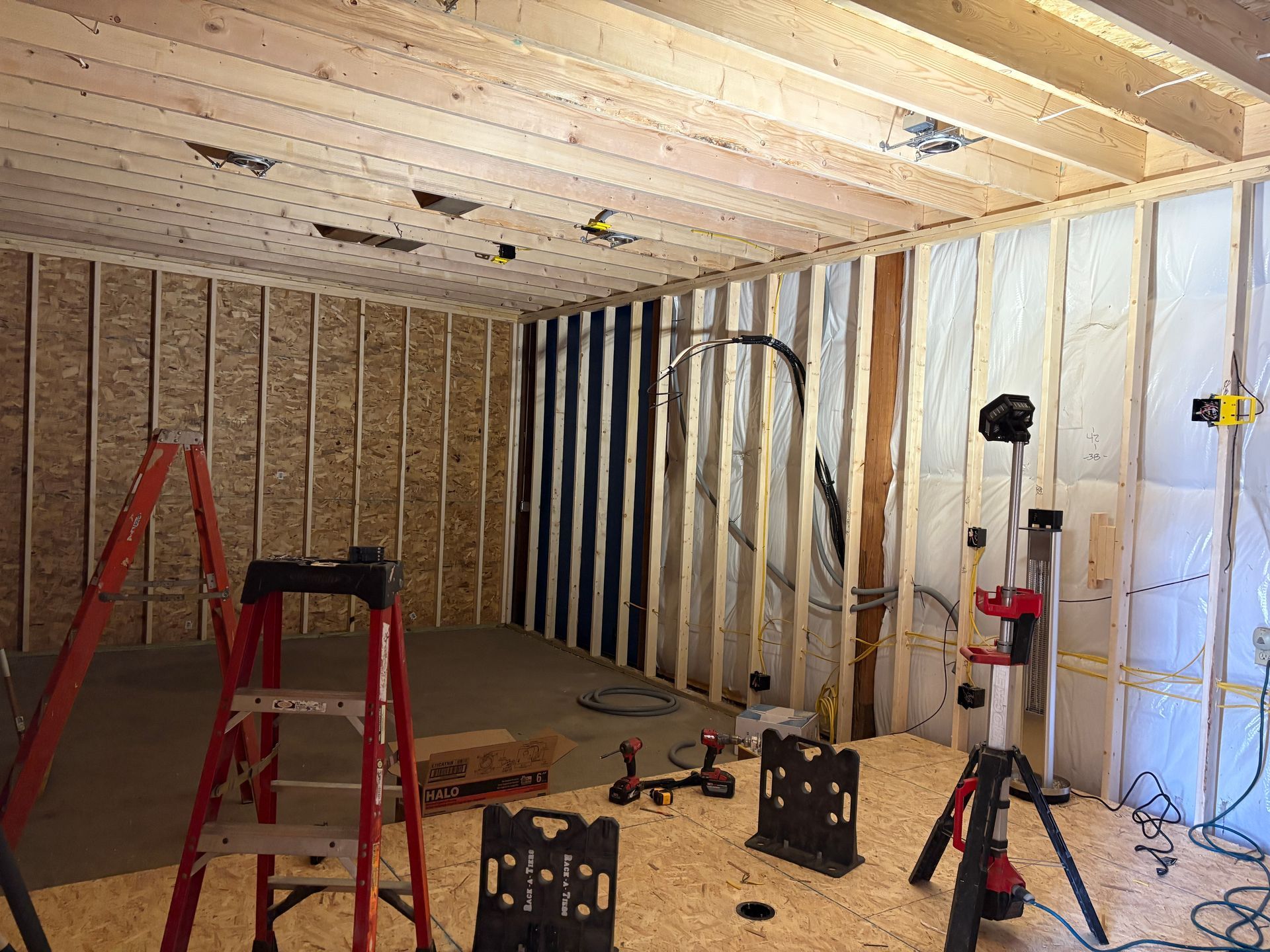 A room under construction with a ladder and tools on the floor.