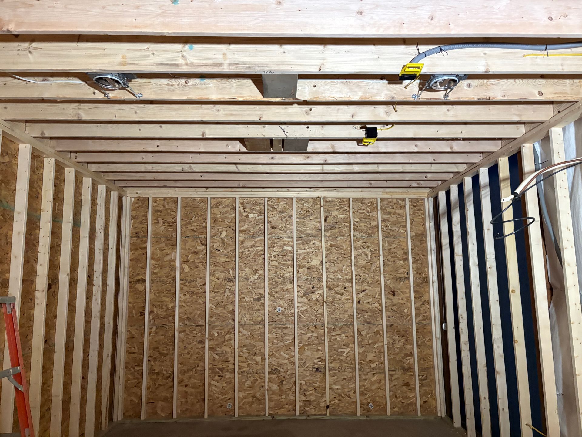 A room with wooden beams and a ladder in the corner.