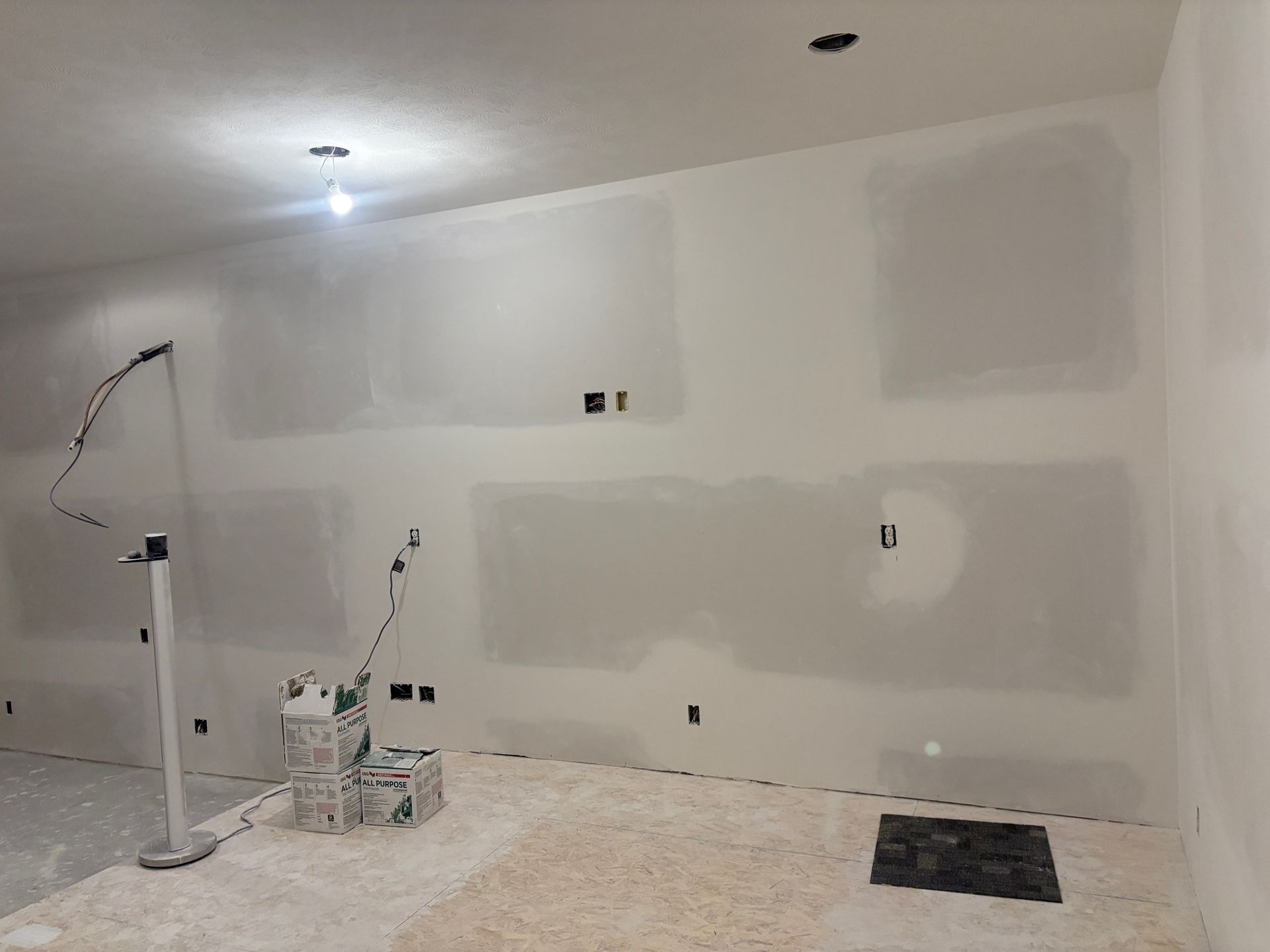A room with a lot of drywall and a light on the ceiling.