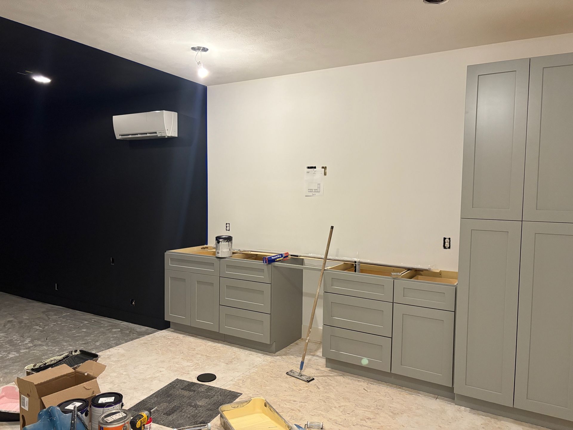 A room with gray cabinets and a mop on the floor.