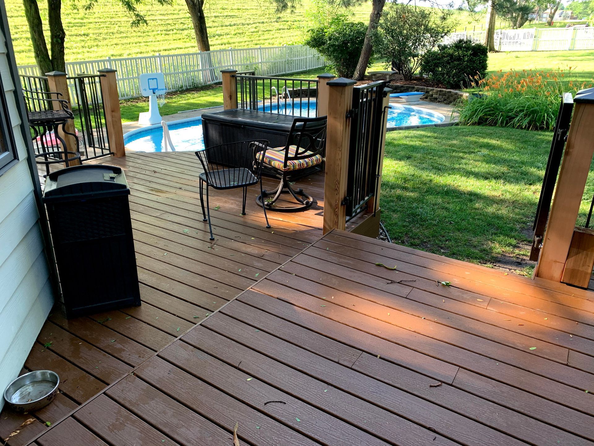 A wooden deck with a table and chairs next to a pool.