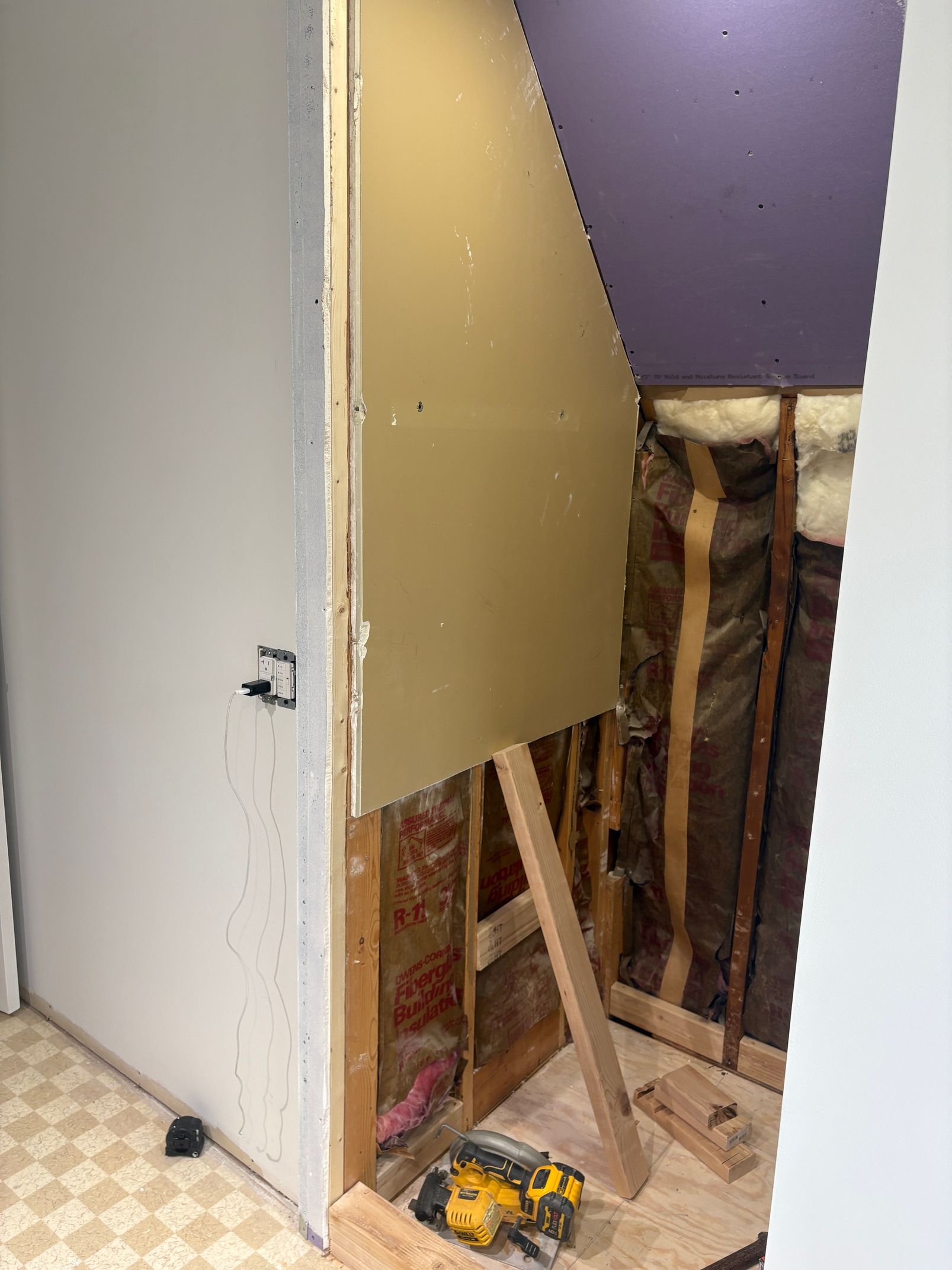 A room with a door and a drill on the floor.