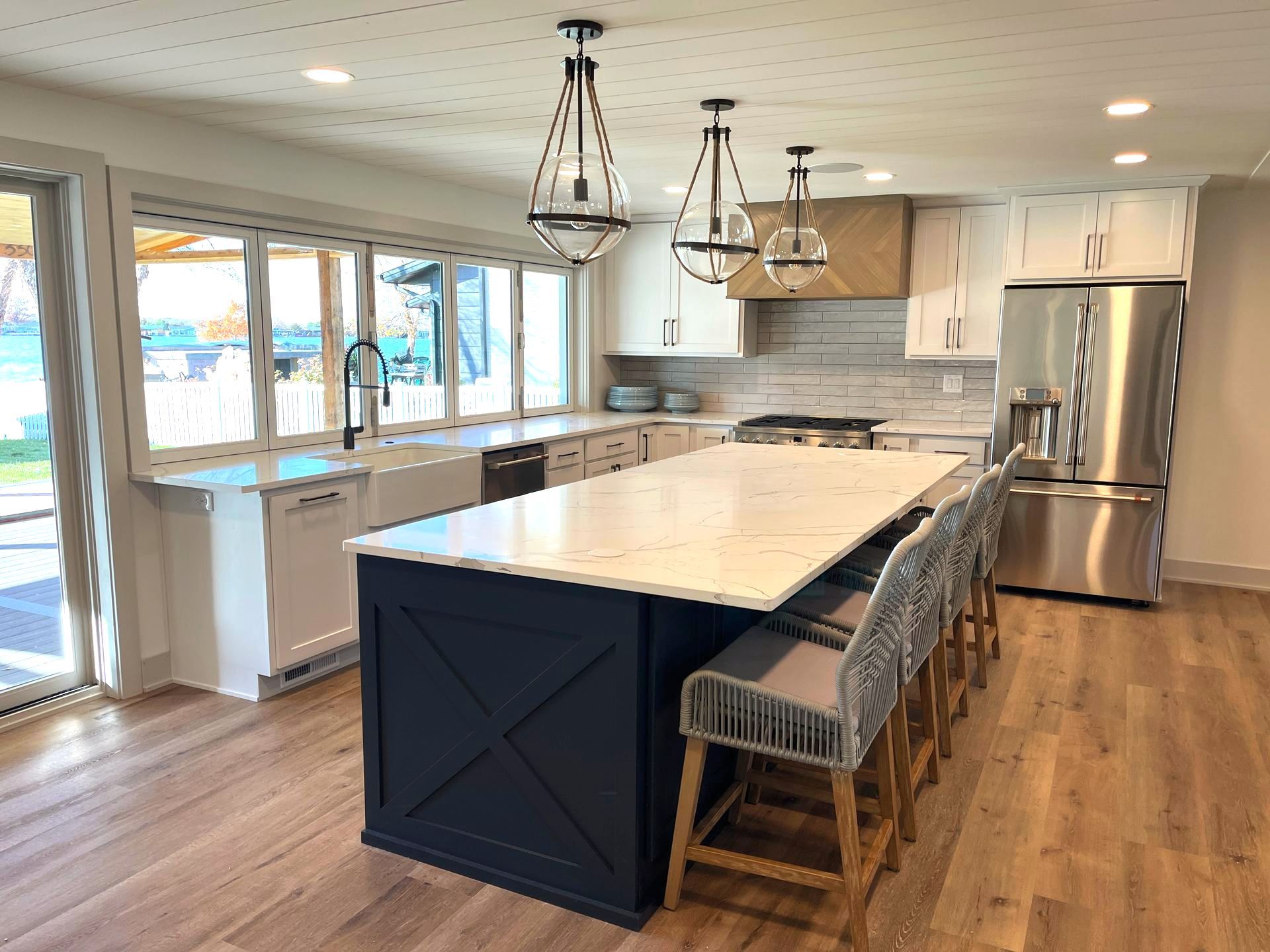 A kitchen with a large island , stainless steel appliances , and white cabinets.