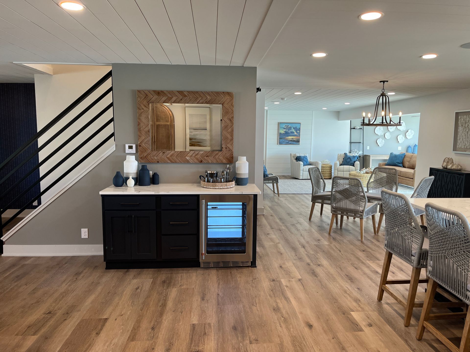 Interior of a modern home with a bar area, dining space, and living room visible; neutral color palette.