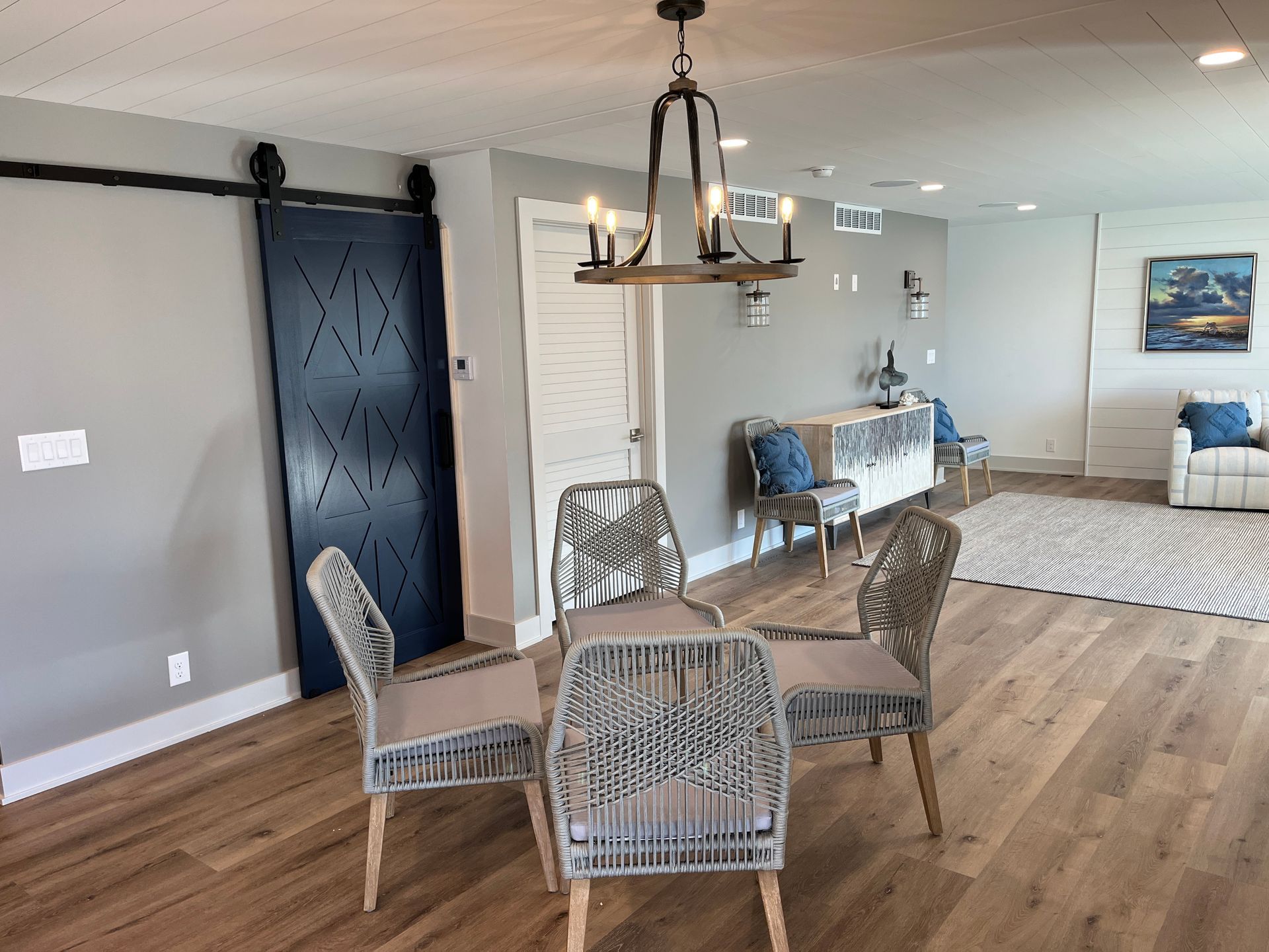 A living room with a dining table and chairs and a sliding barn door.