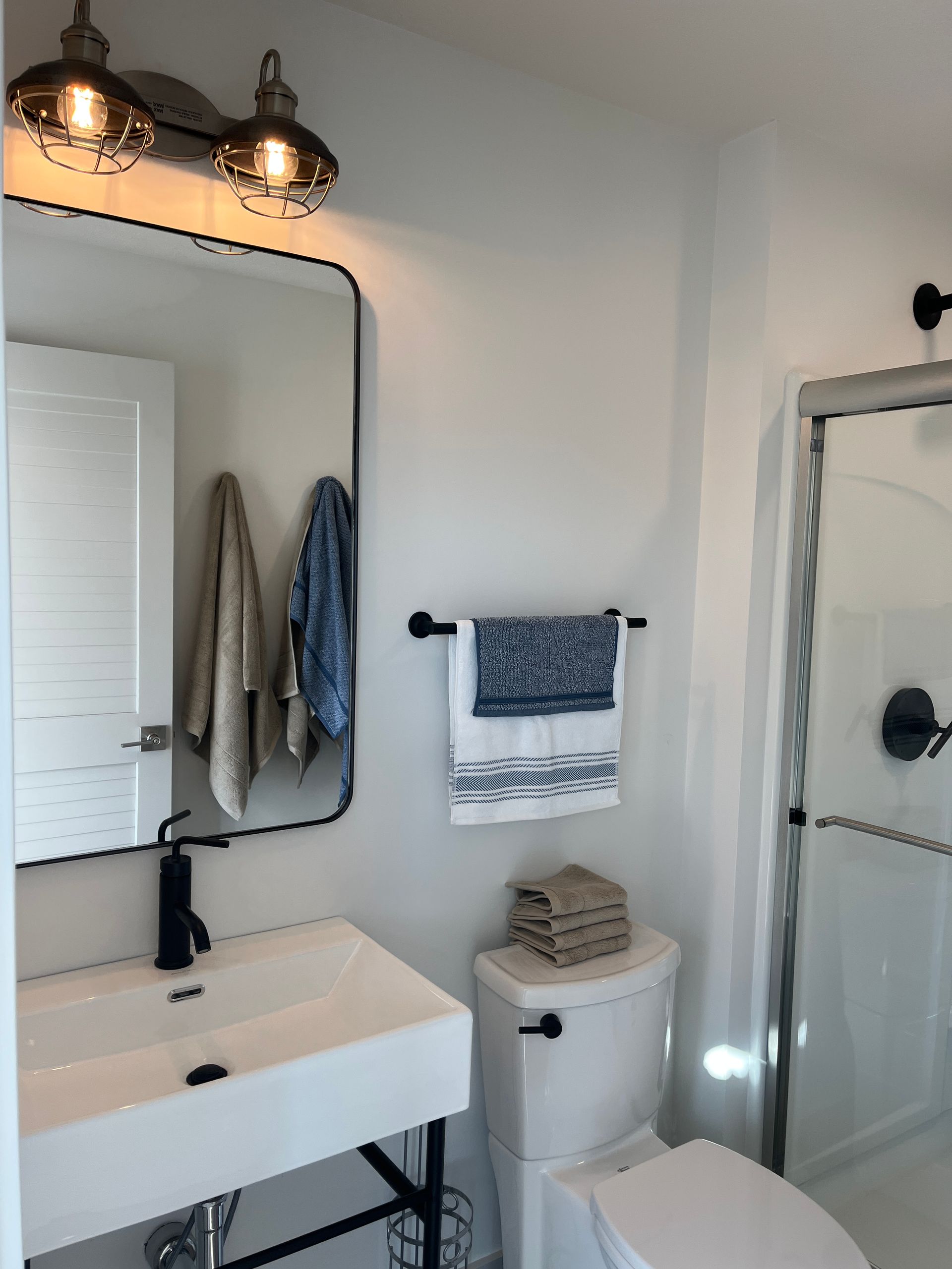 A bathroom with a sink , toilet , shower and mirror.