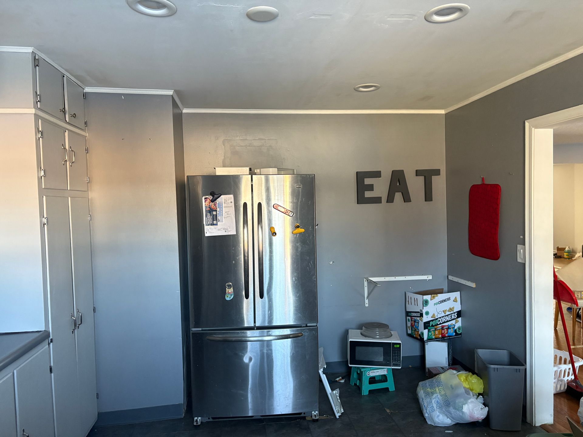 Kitchen with gray walls, stainless steel refrigerator, and the word 