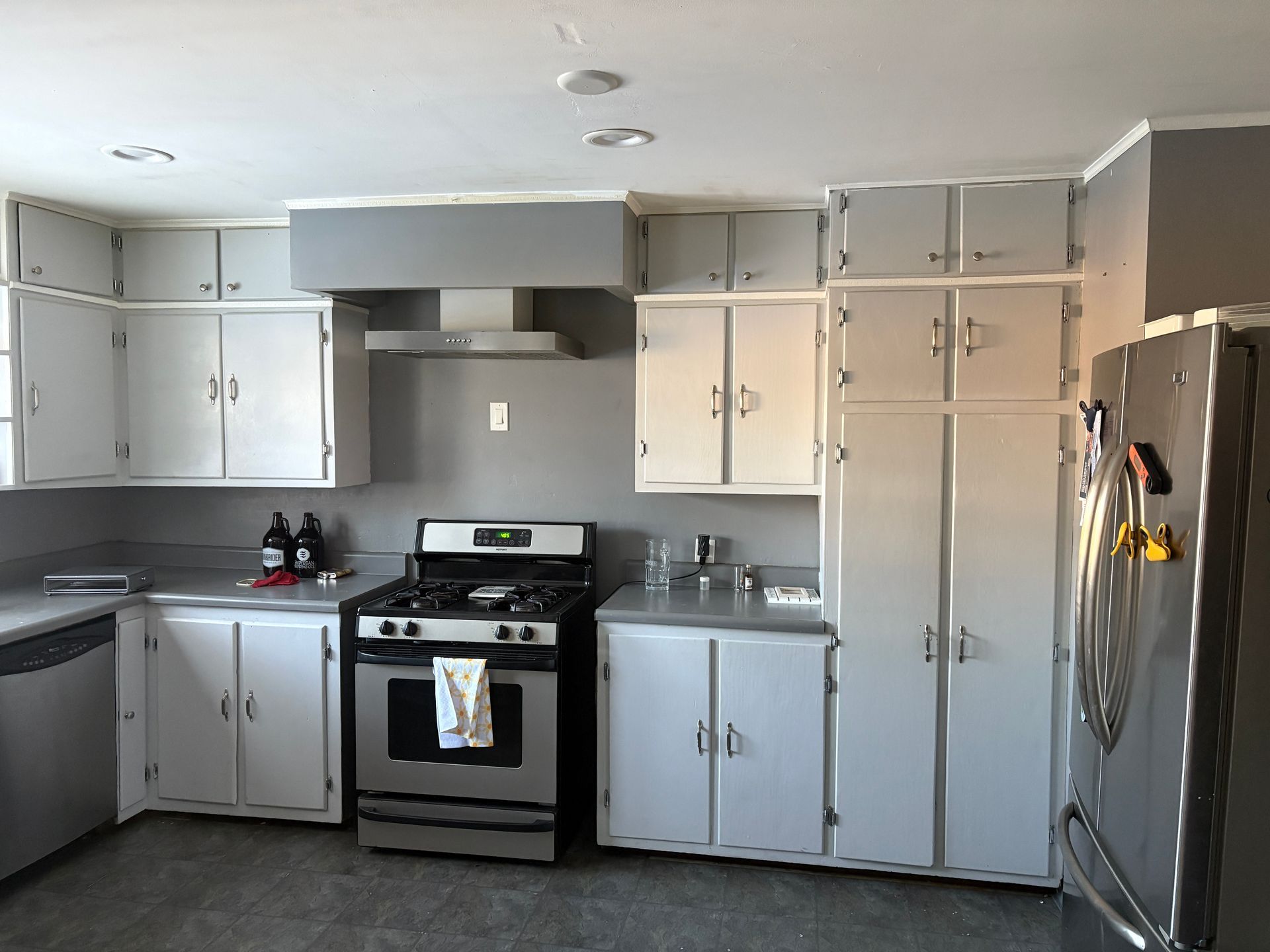 Gray and white kitchen with cabinets, stove, and refrigerator.