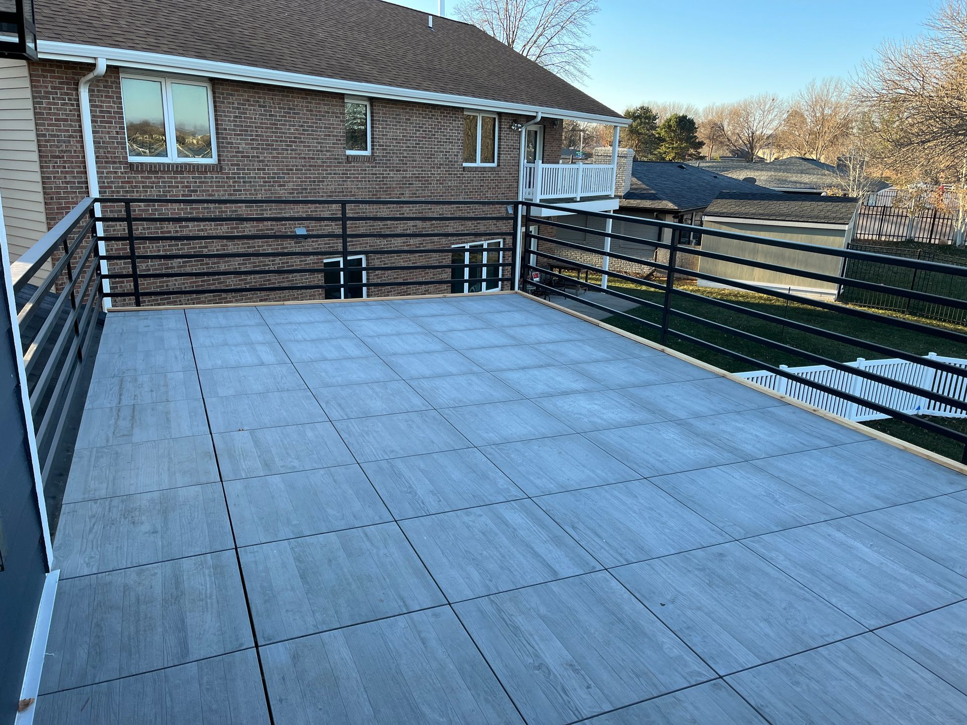 A balcony with tiles and a metal railing on the side of a house.