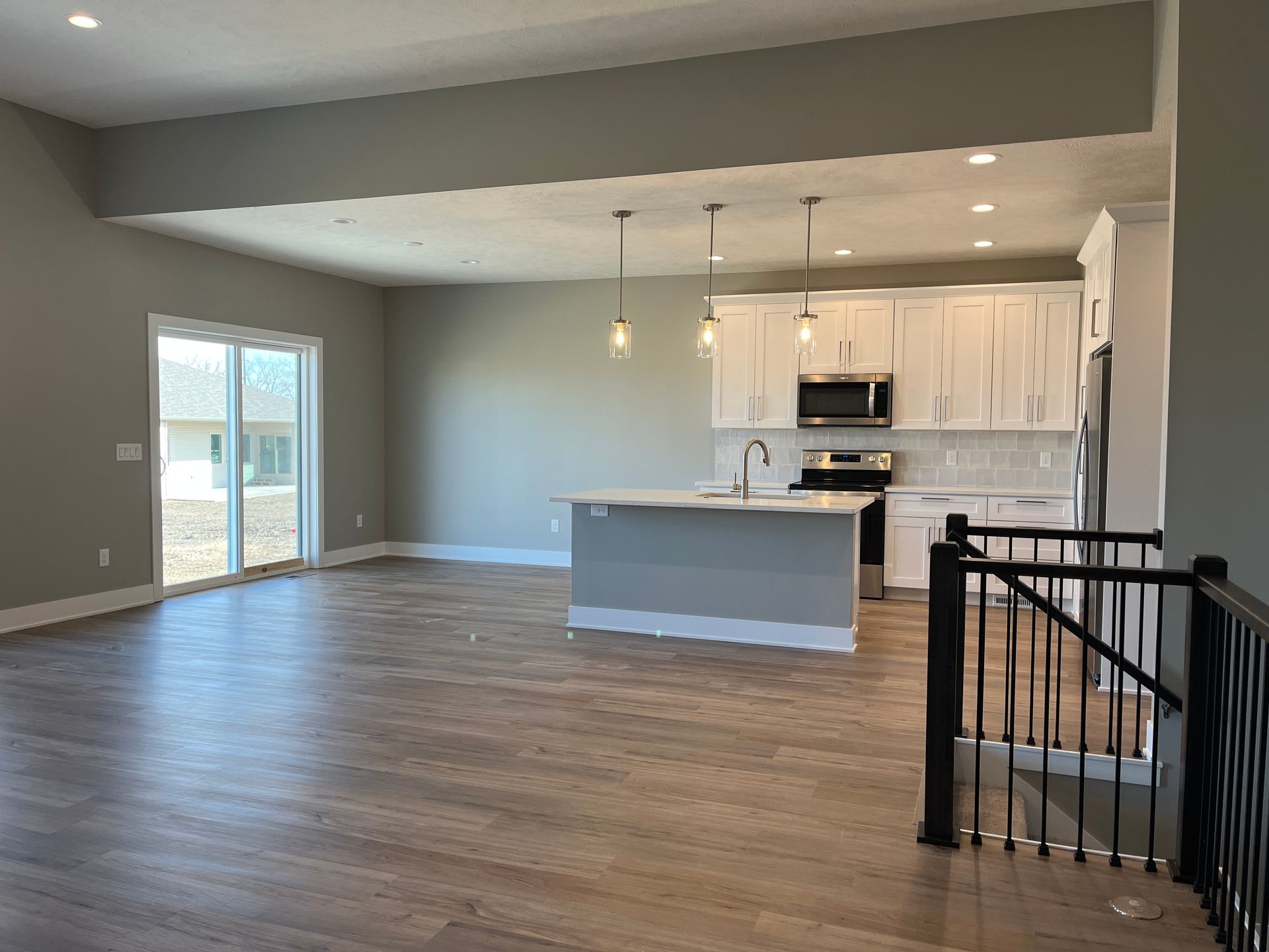 A large empty room with a kitchen in the background.