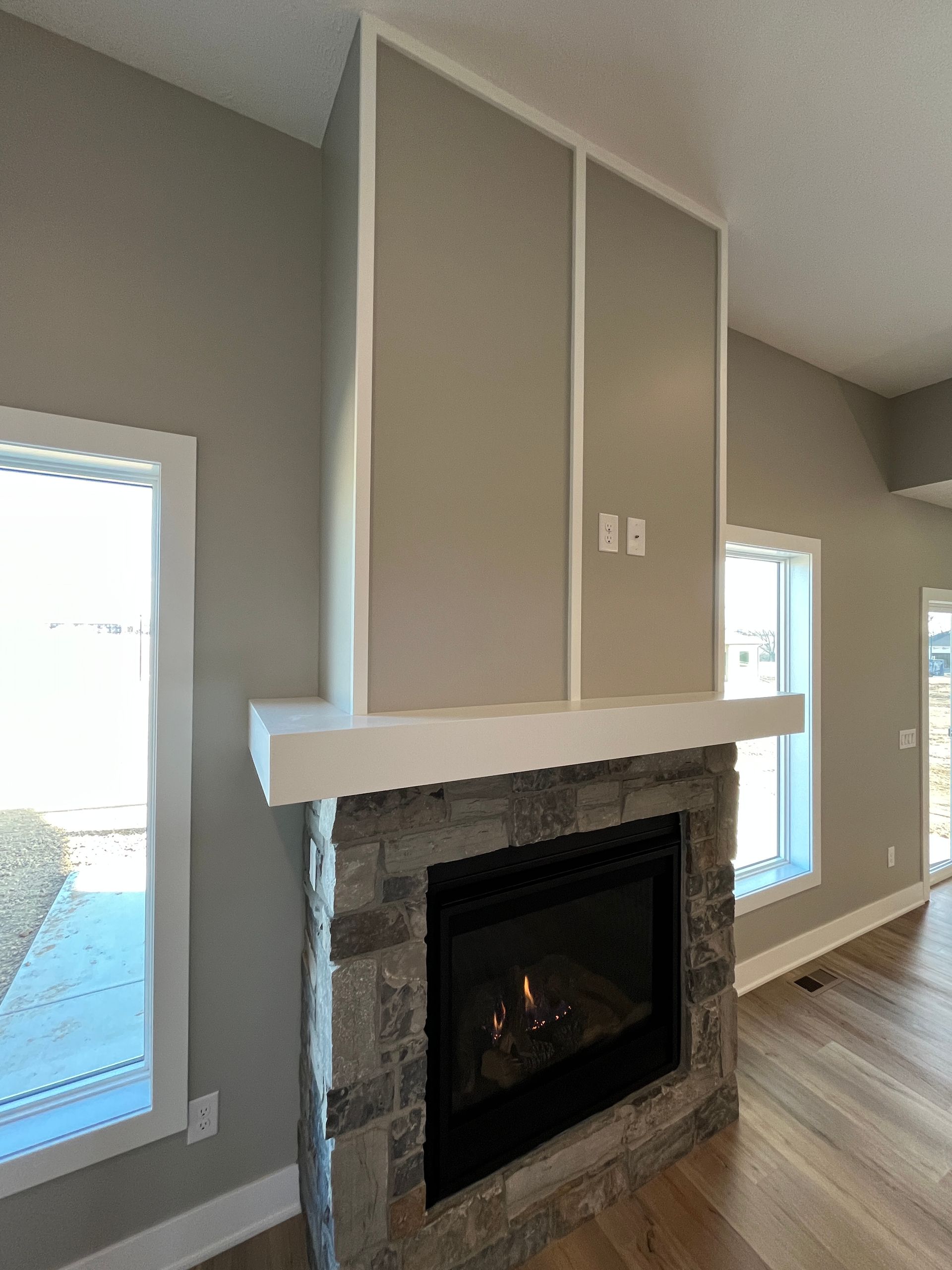 A living room with a fireplace and two windows.