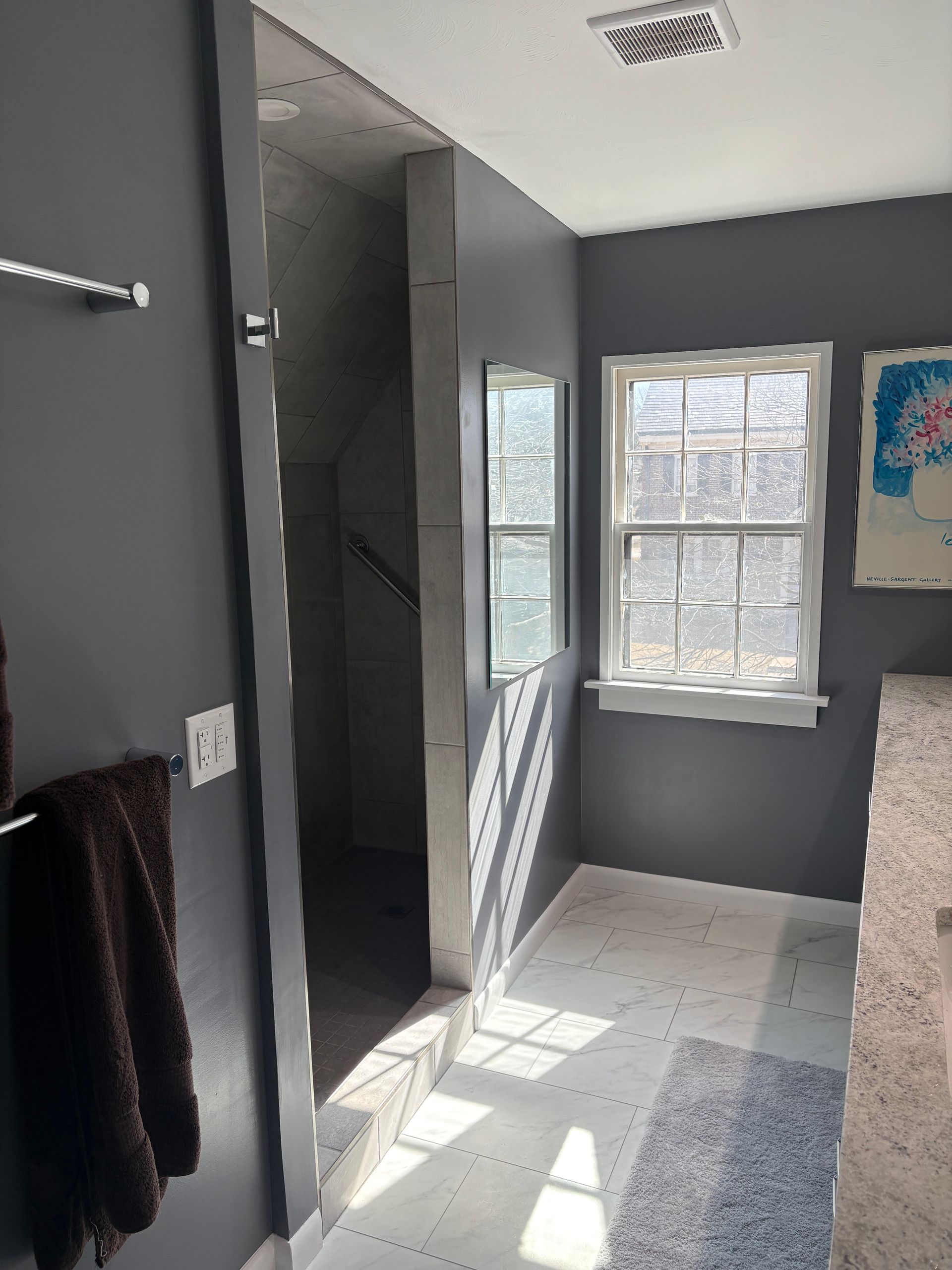 Dark gray bathroom with a narrow shower entrance and two windows.