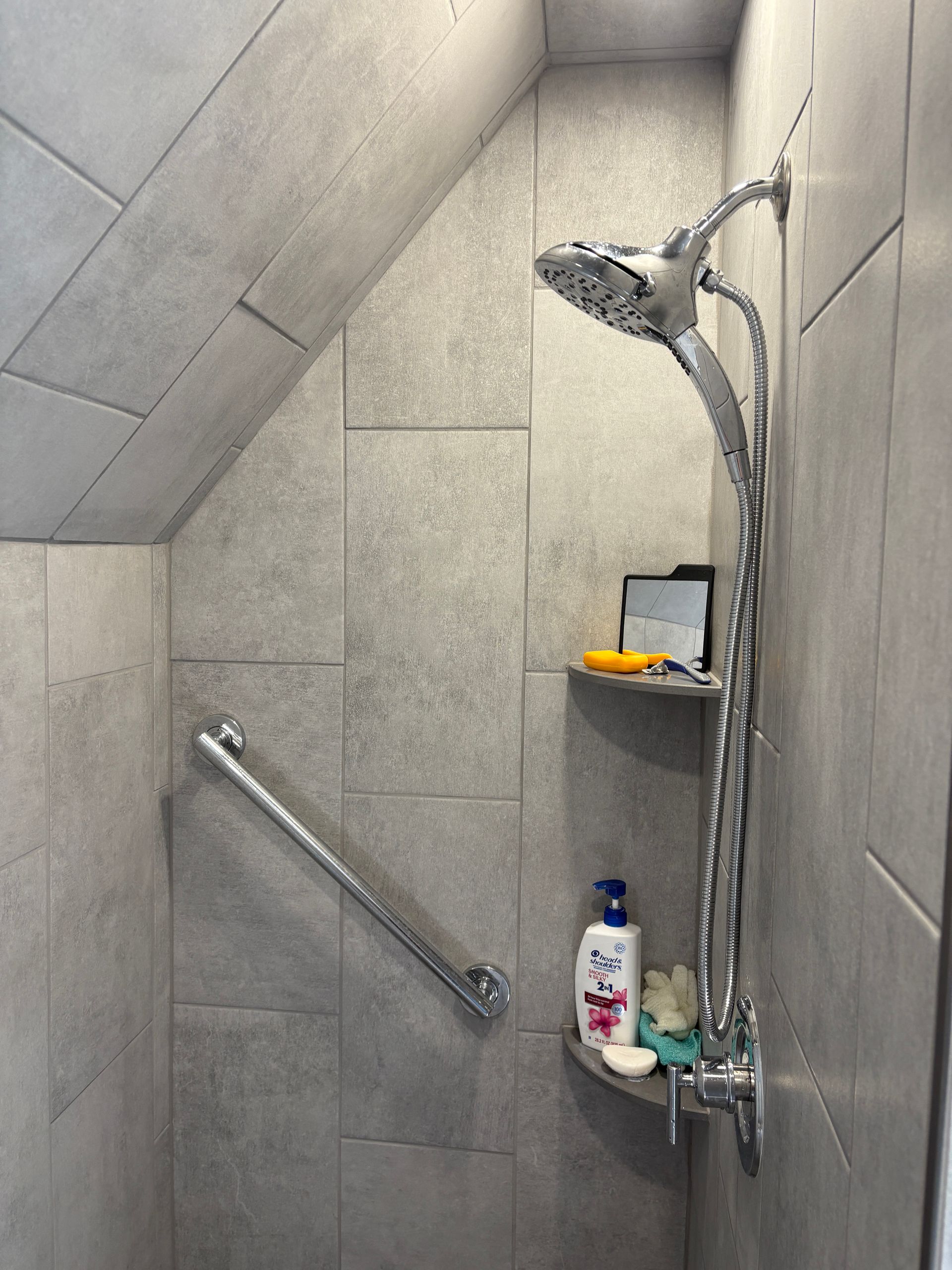 A shower with a hand rail and a shower head.