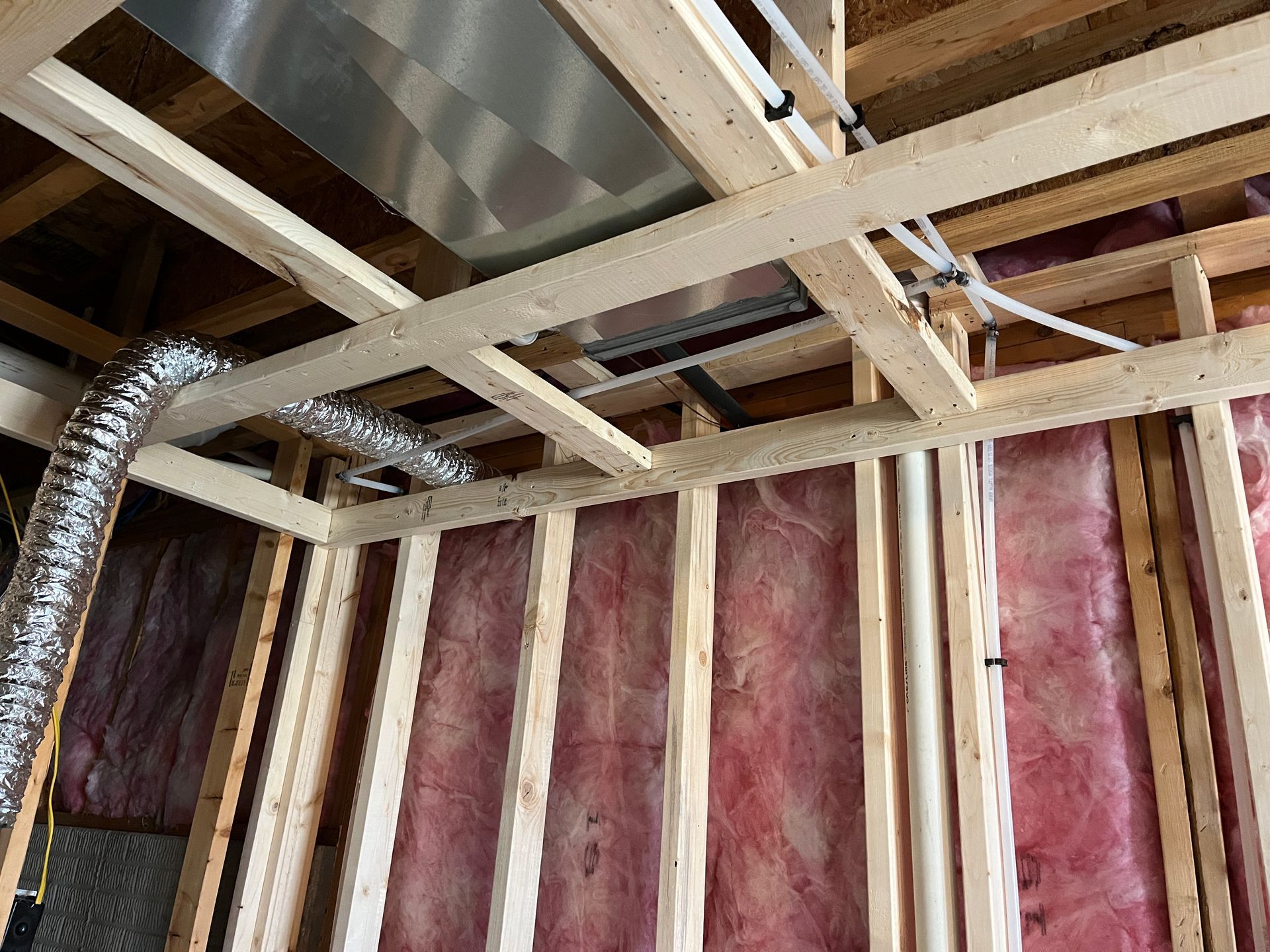 A room under construction with wooden beams and insulation.