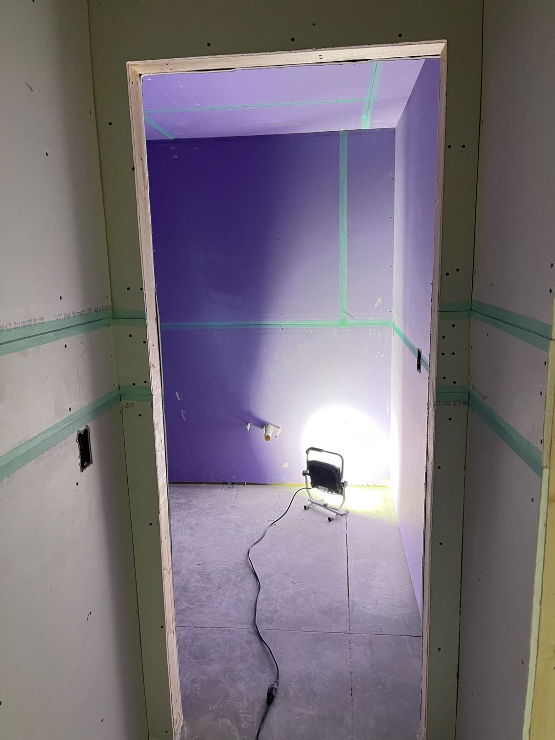 A room with purple walls and a light on the floor.