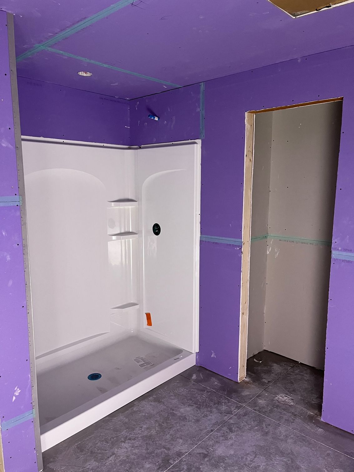 A bathroom with purple walls and a white shower stall.