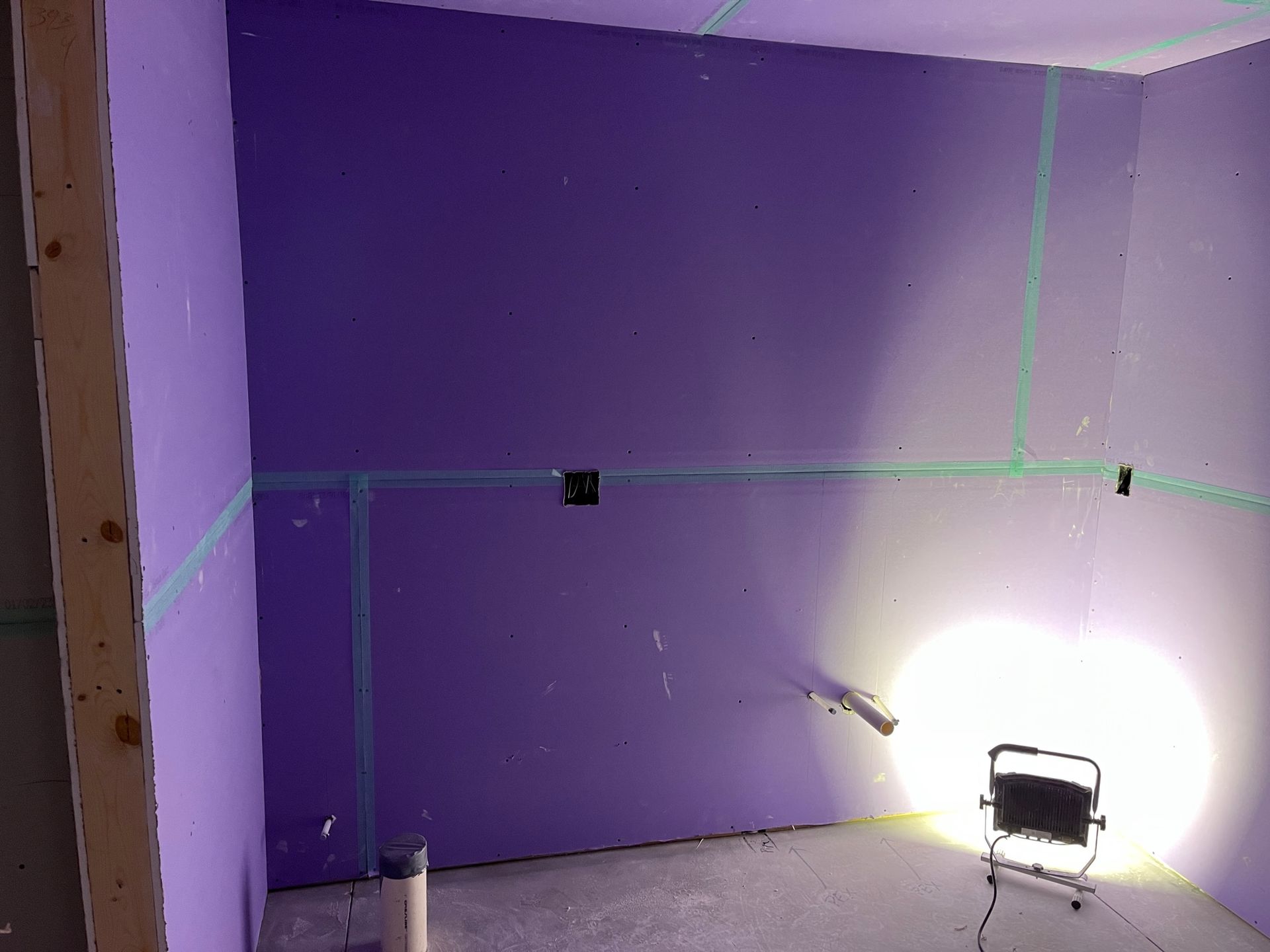 A room with purple walls and a light on the floor.