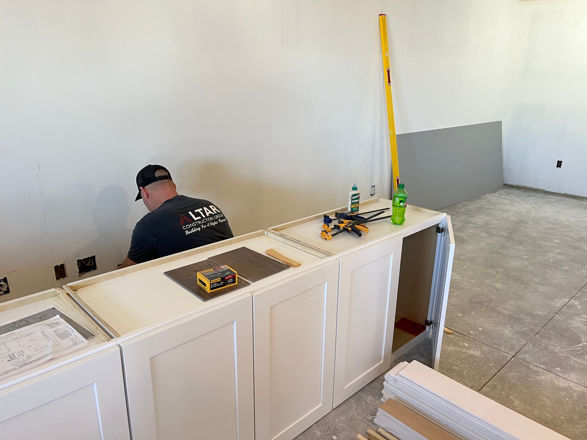 A man is working on a kitchen counter in a room.