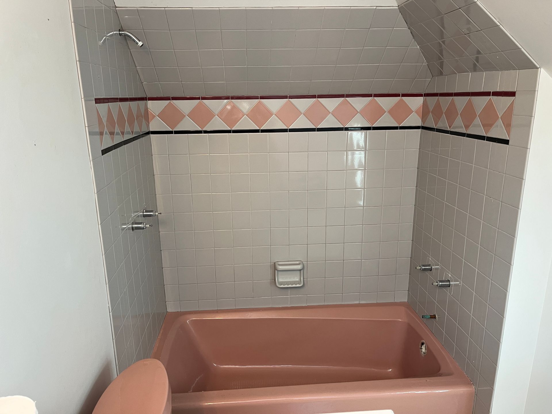 A pink bathtub in a bathroom next to a toilet