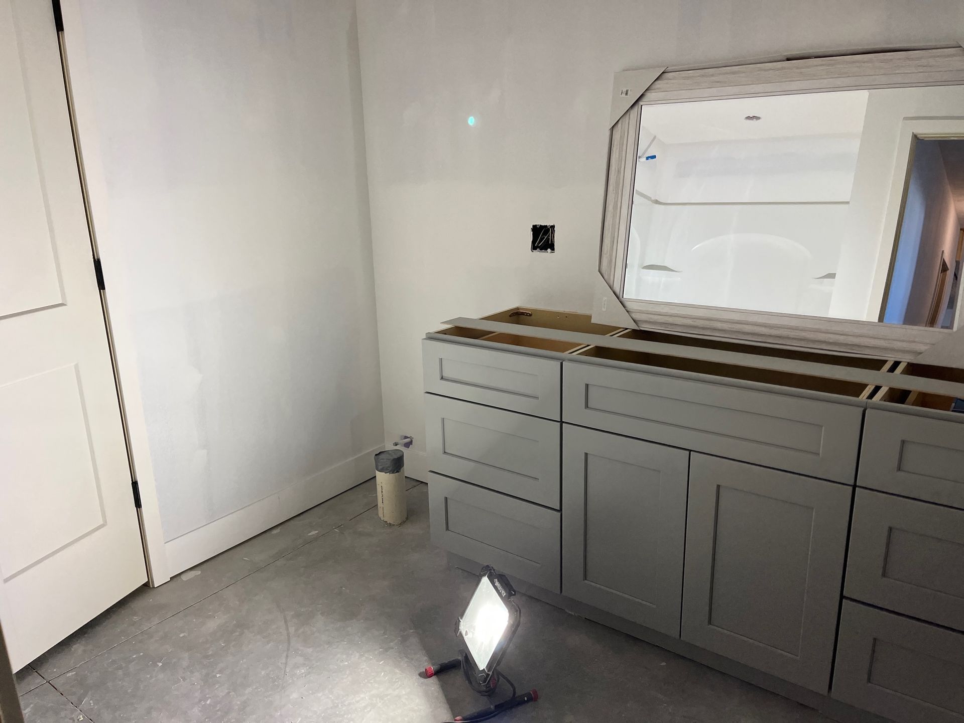 A bathroom with gray cabinets and a mirror.