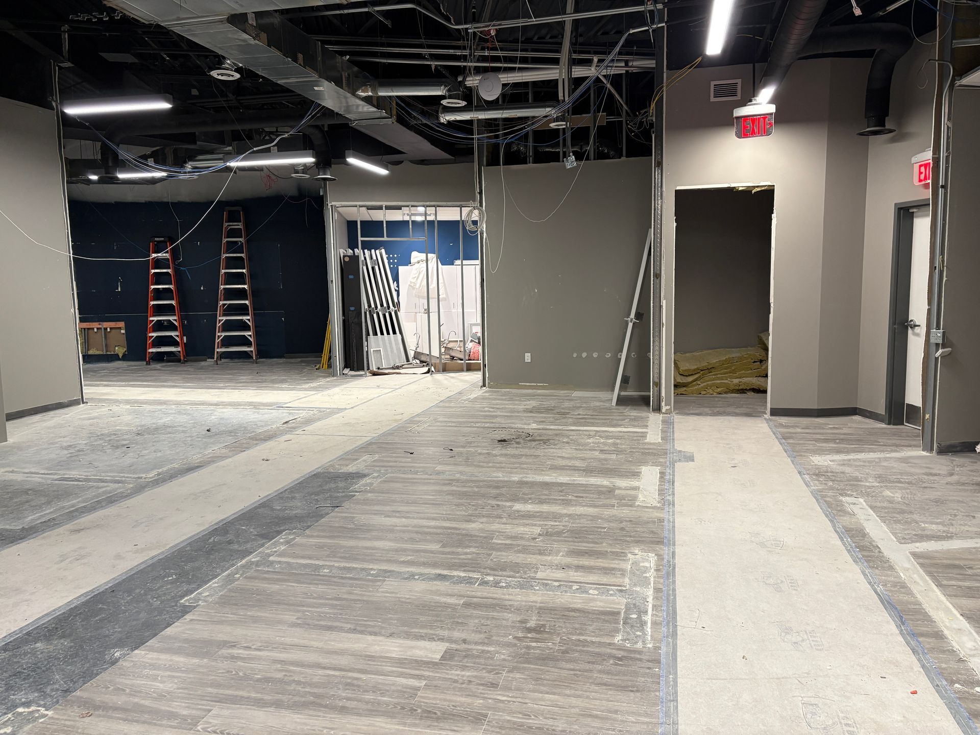 Interior during renovation with exposed beams, bare walls, and construction debris.