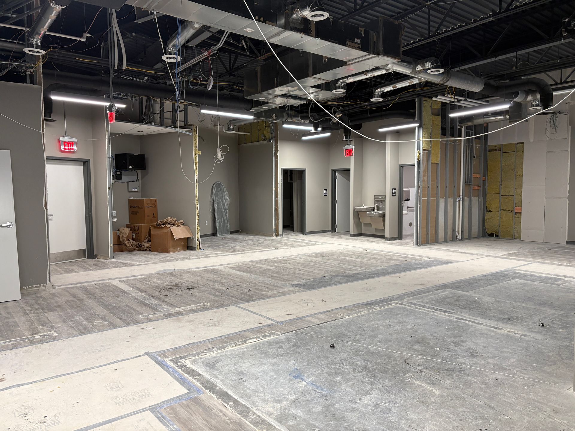 Interior of unfinished commercial space. Gray concrete floor, exposed ceiling, partial walls, and doorways.