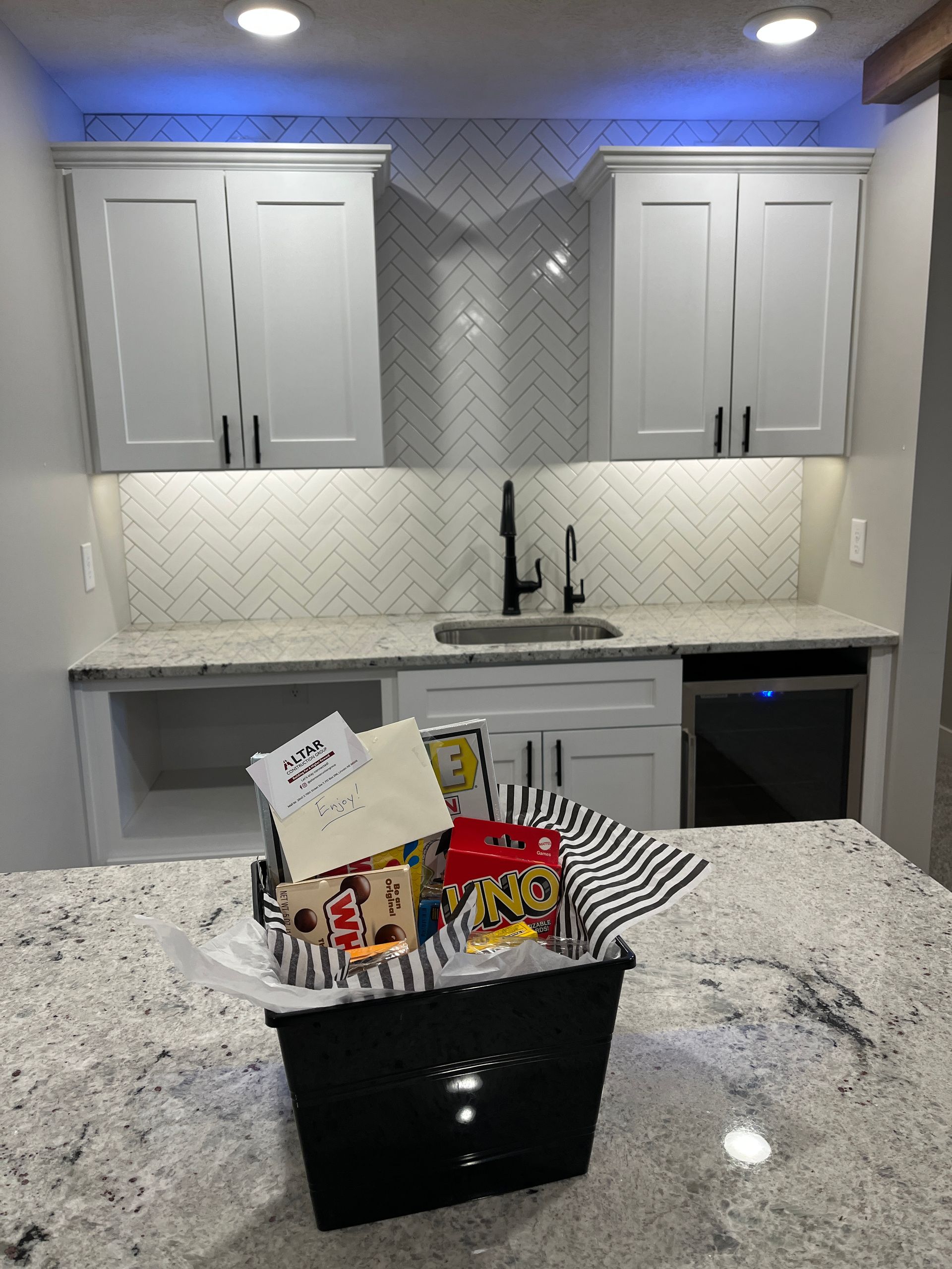 A basket of snacks is sitting on a counter in a kitchen.