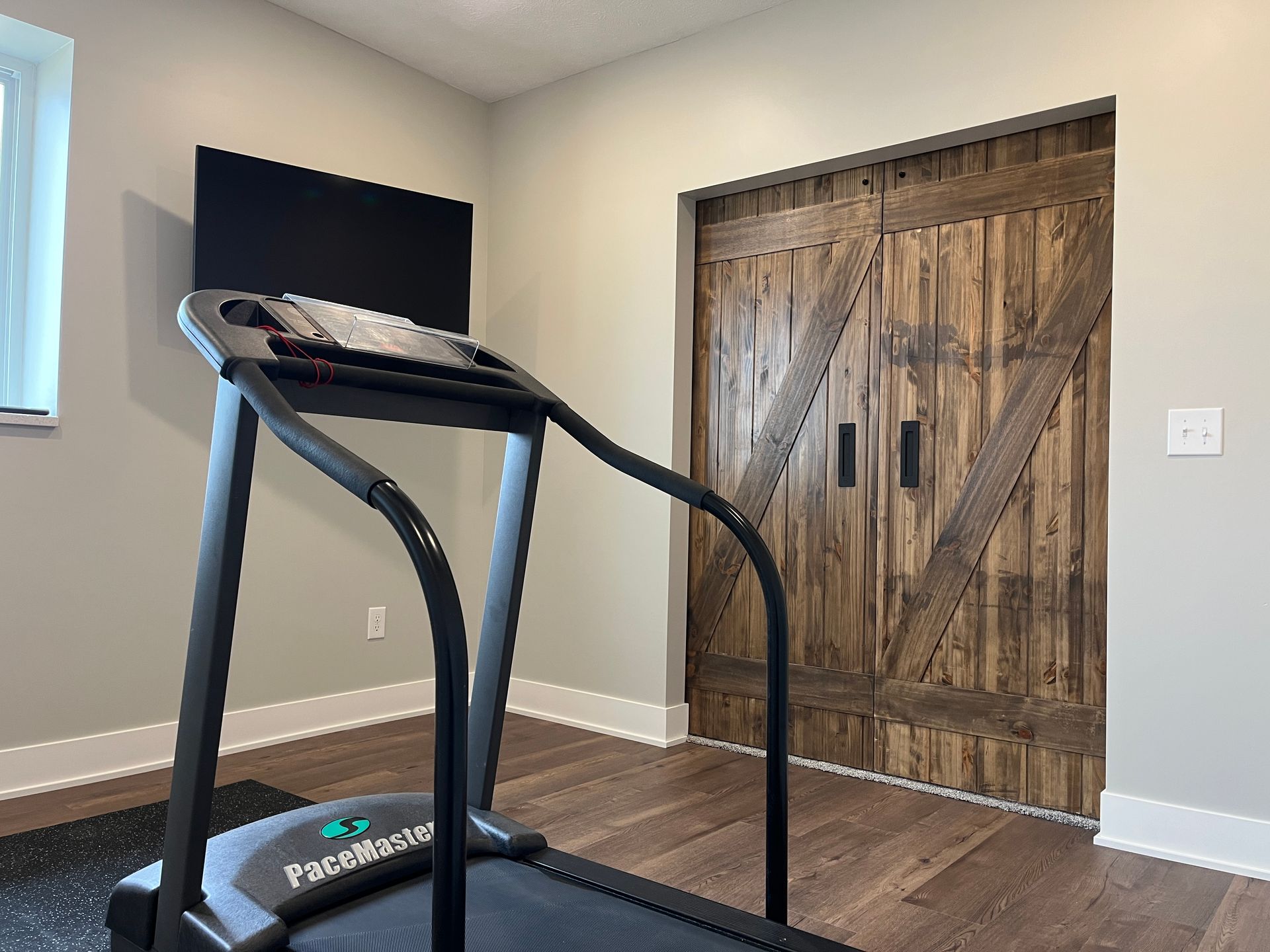 A treadmill is sitting in a room next to a wooden door.