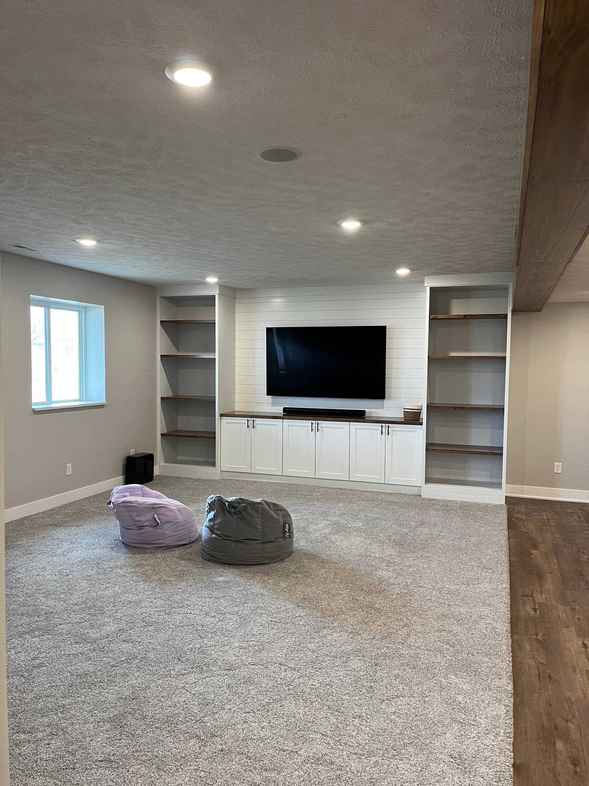 An empty basement with a flat screen tv on the wall.
