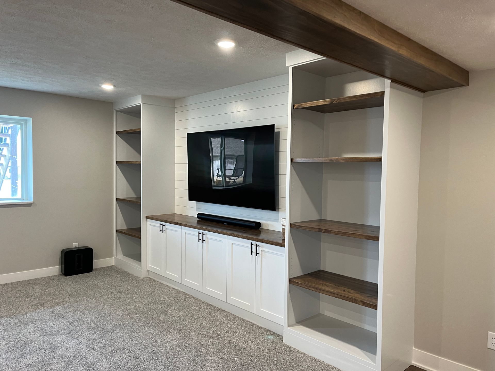 A living room with a flat screen tv and shelves.