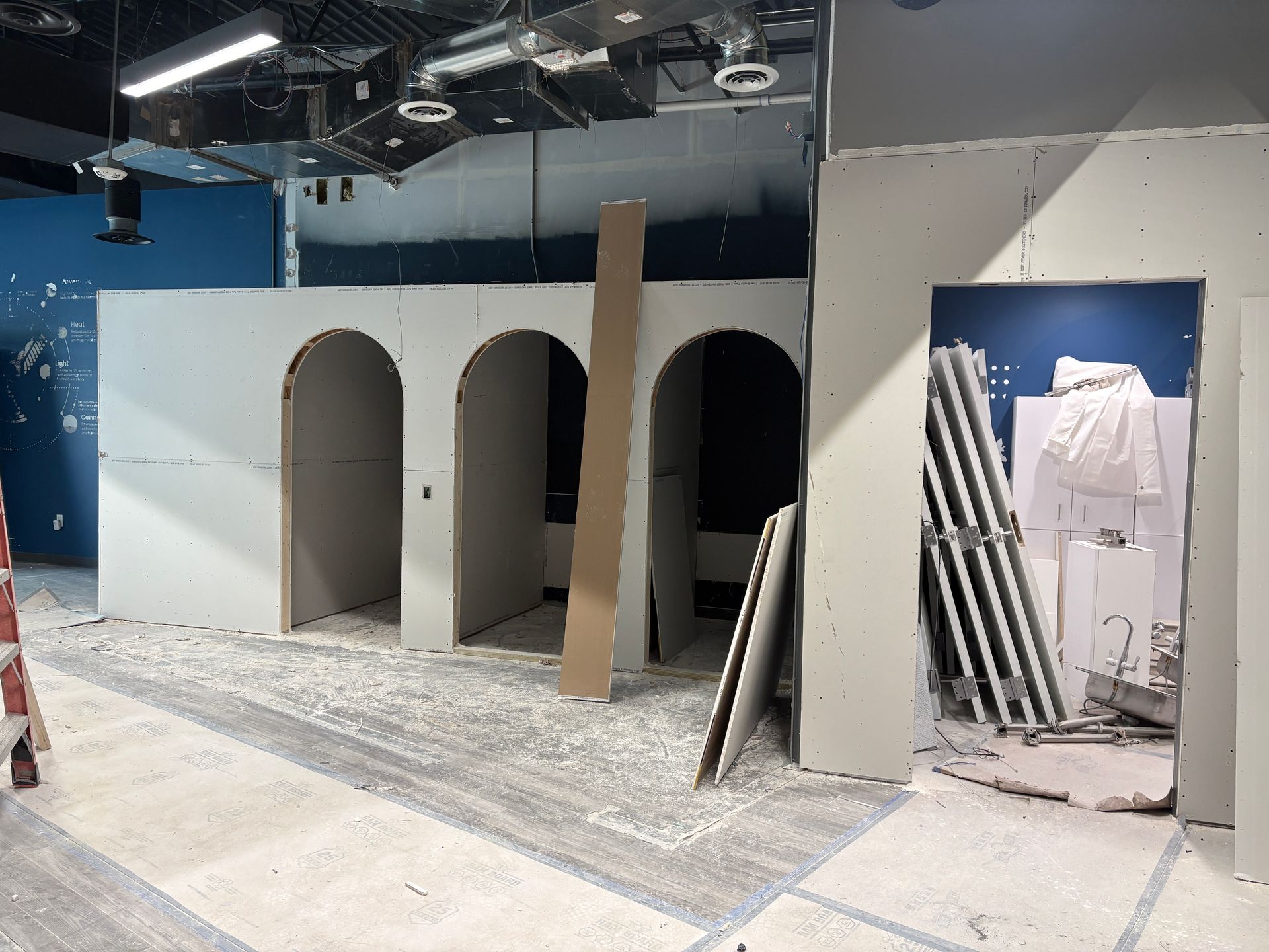 Construction site with drywall walls and arched openings; unfinished interior.