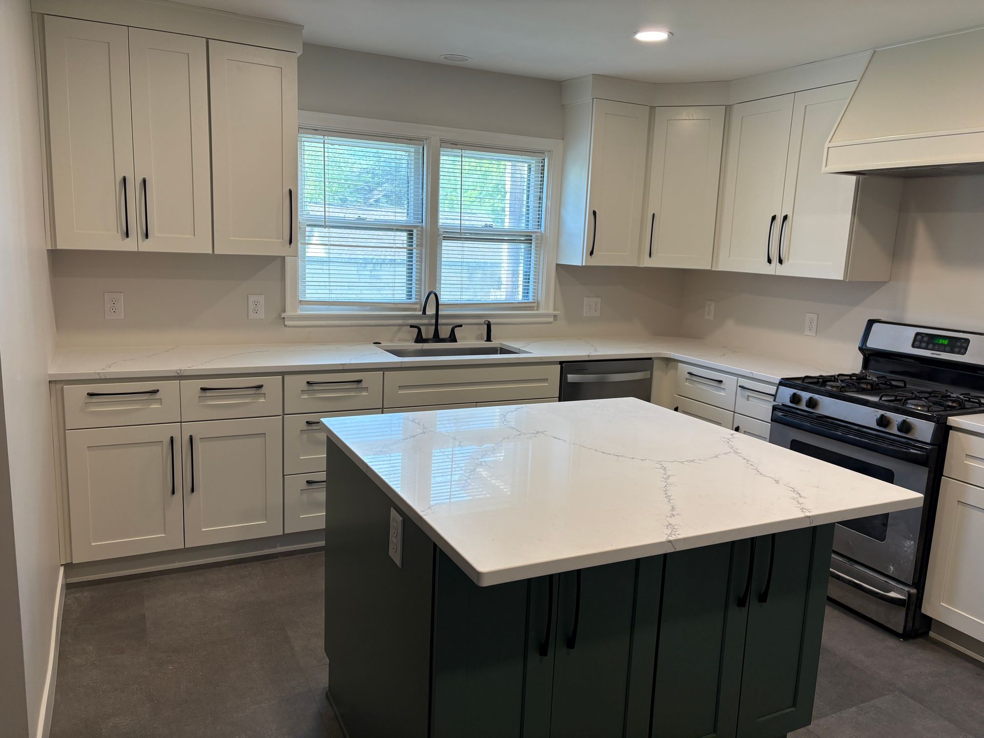 Modern kitchen with white cabinets, green island, and stainless steel appliances.