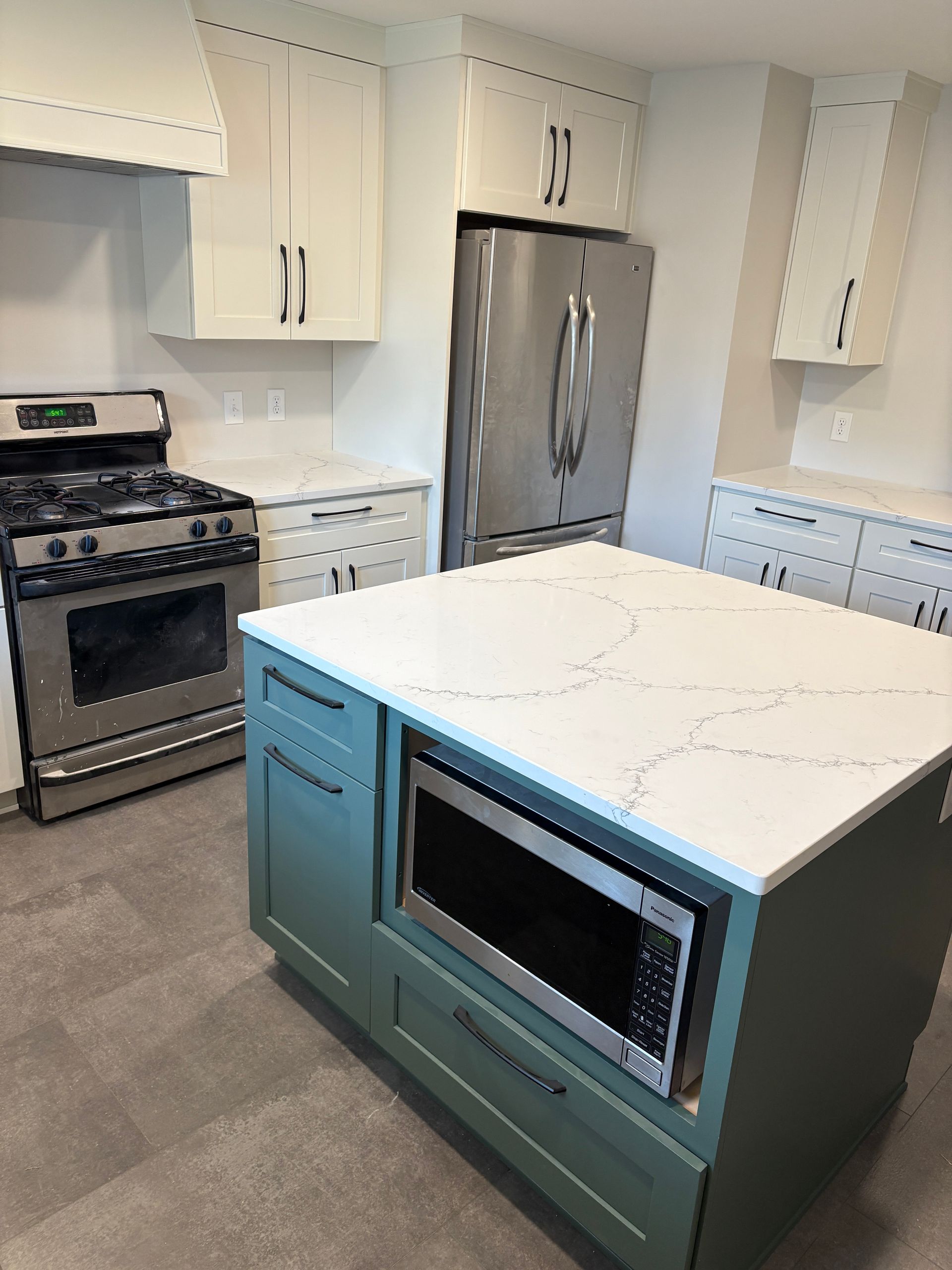 Kitchen with blue island, white countertops, stainless steel appliances, and white cabinets.