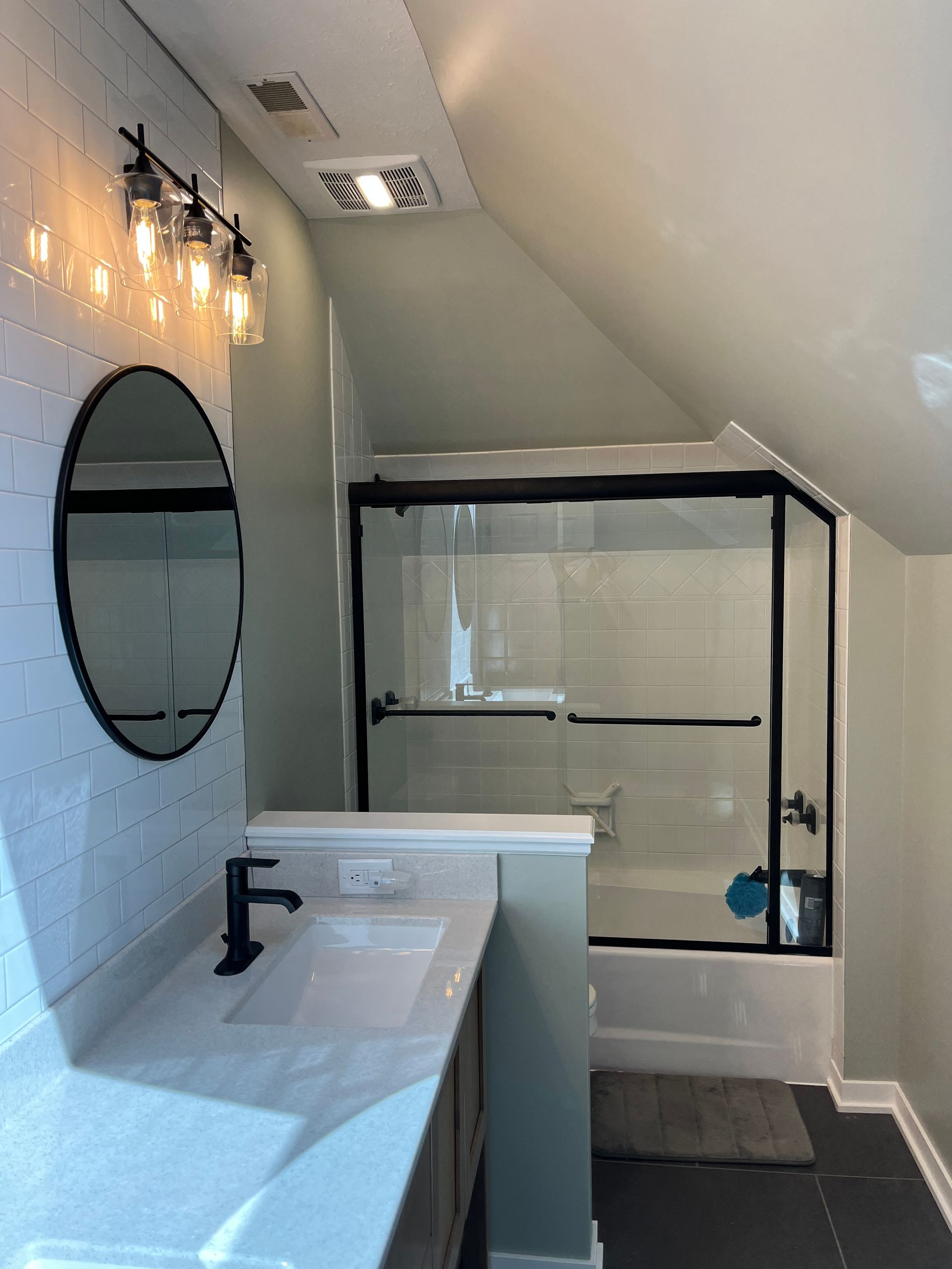 A bathroom with a sink , mirror , tub and shower.