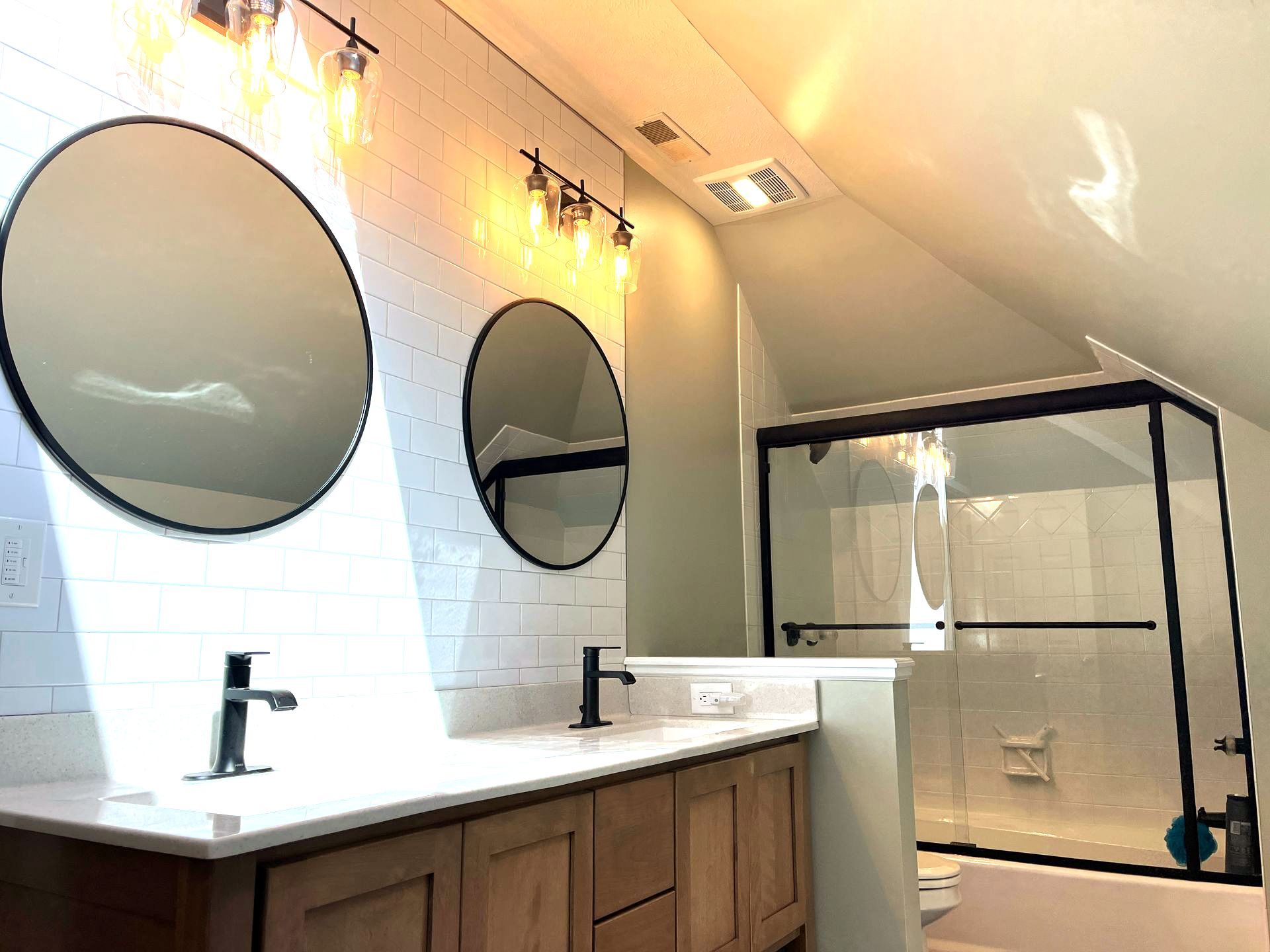 A bathroom with two sinks , two mirrors , a toilet and a shower.