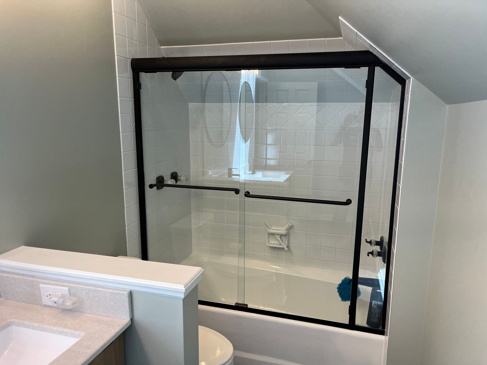 A bathroom with a sliding glass shower door and a bathtub.
