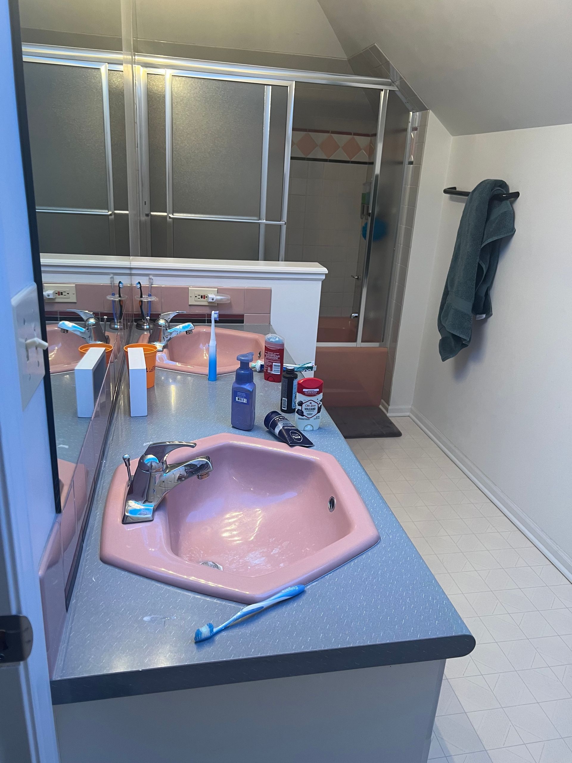 A bathroom with a pink sink and a toothbrush on the counter