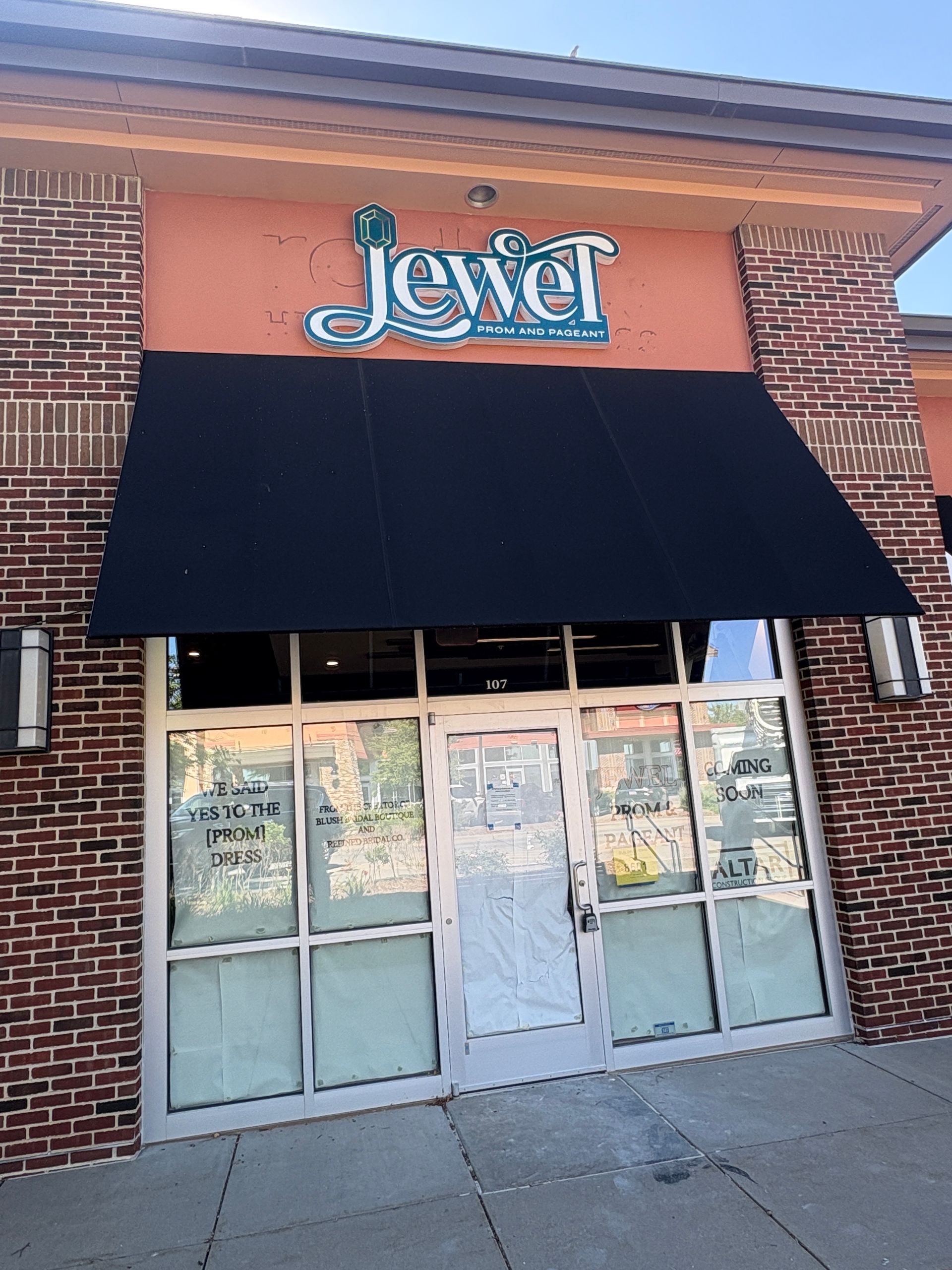 Jewel restaurant storefront with black awning, glass doors, and brick facade.