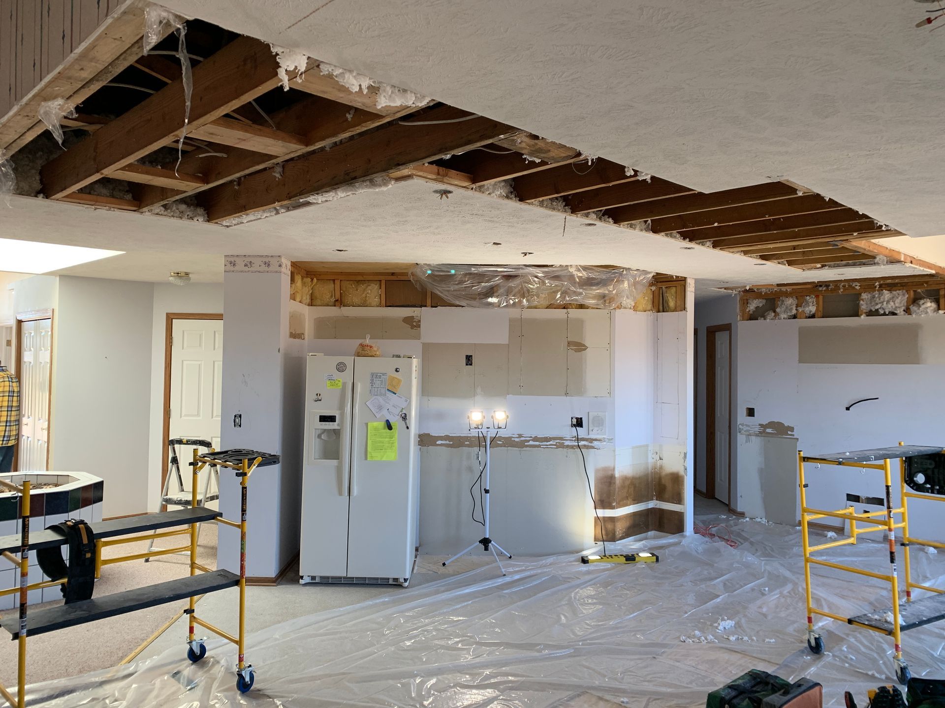 A kitchen under construction with a refrigerator and scaffolding