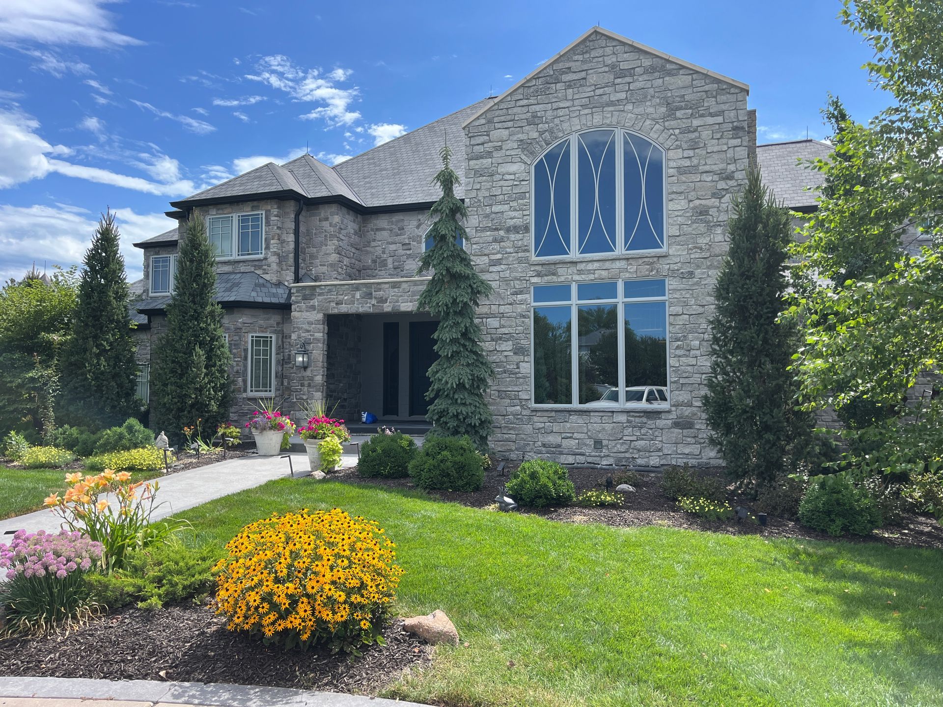 A large stone house with a lot of windows and a lush green lawn.