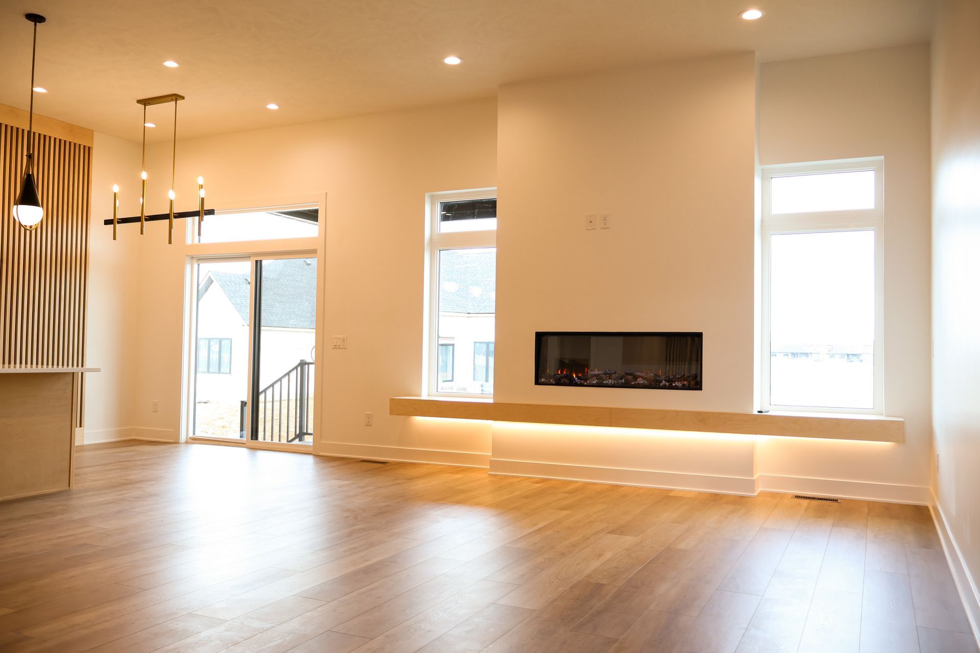 Spacious living room with fireplace, windows, and light wood flooring.