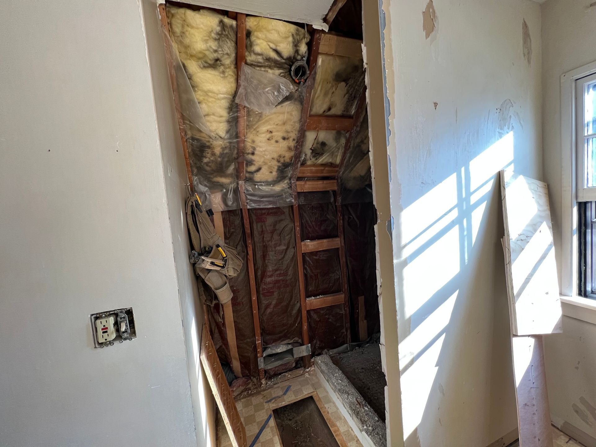 Renovation: wall torn down, exposing insulation and framing, near window.