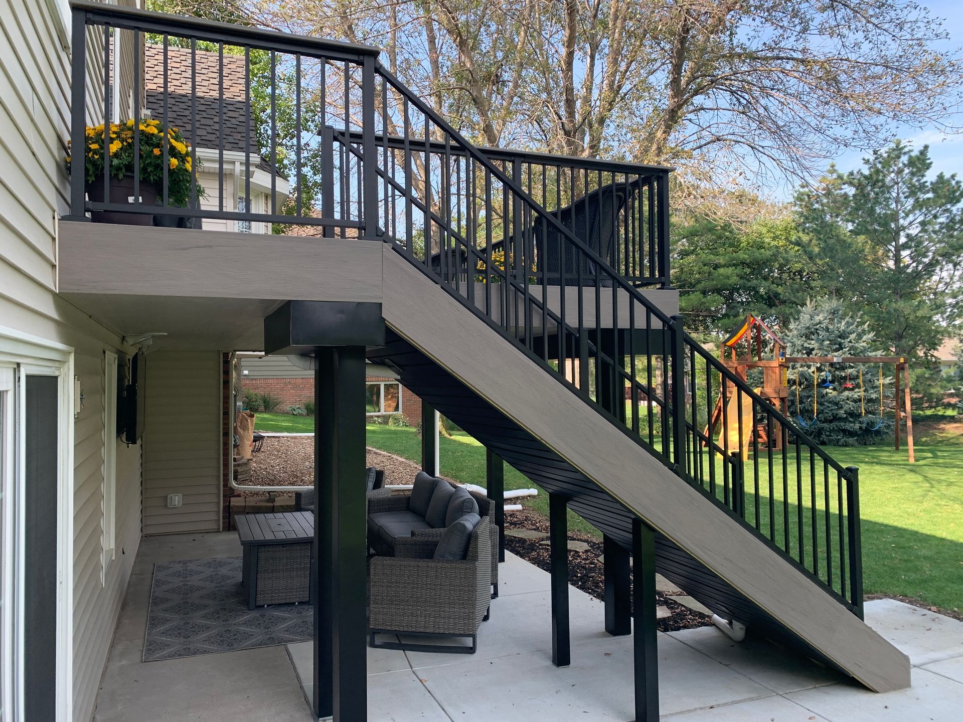 A deck with stairs leading up to it and a couch and chairs on it.