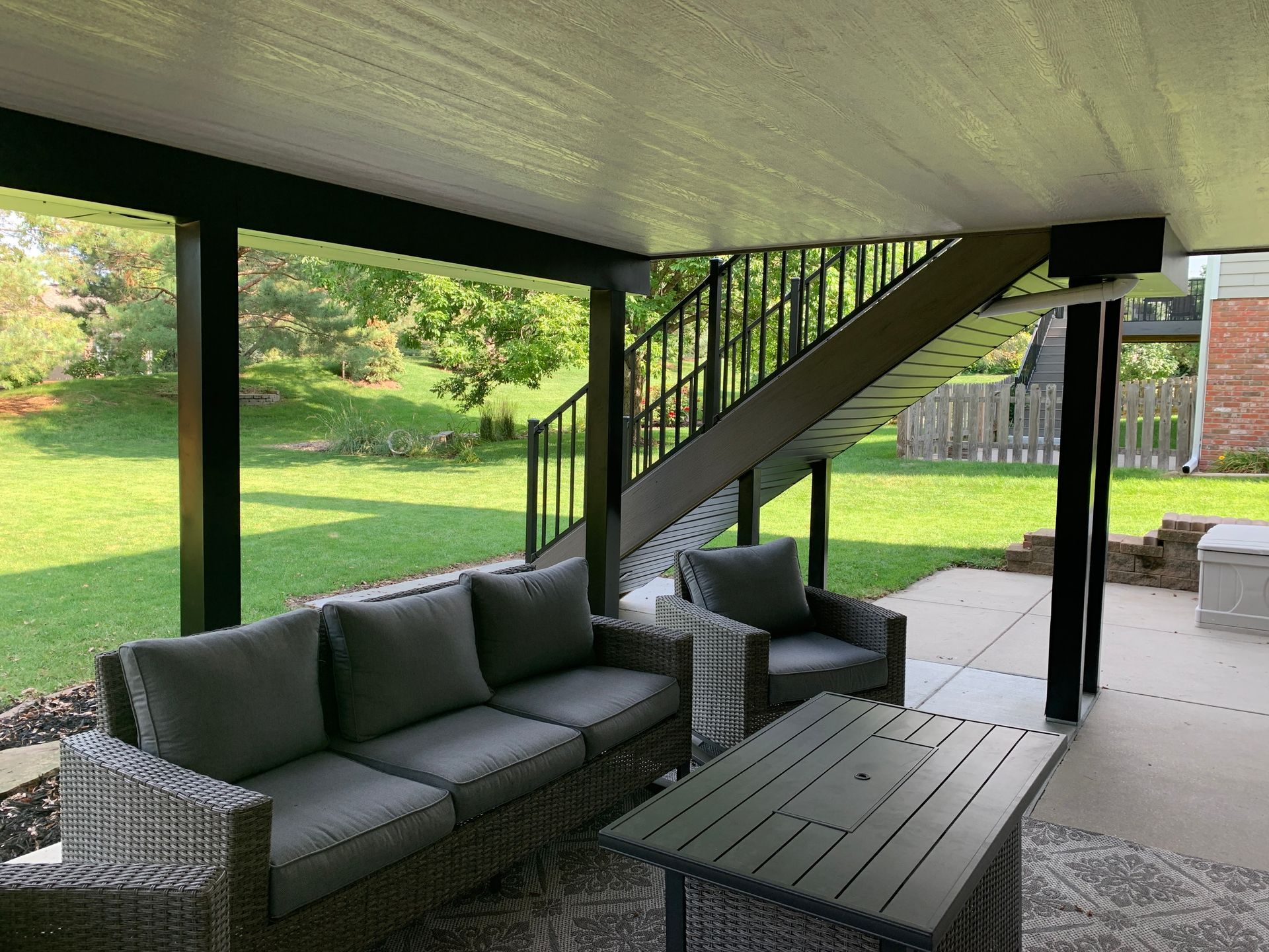 A patio with a couch , chairs , table and stairs.
