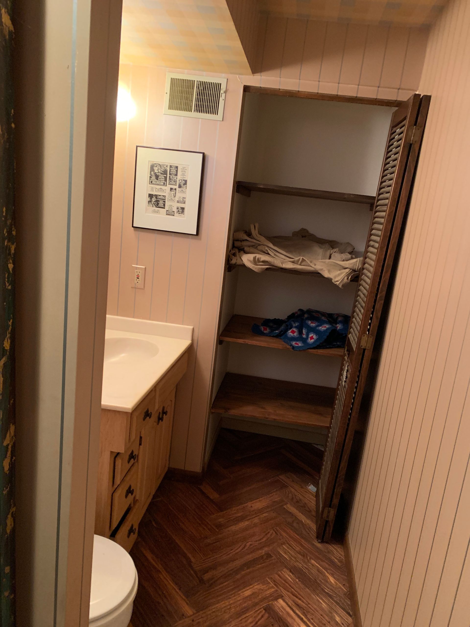 A bathroom with a toilet a sink and a closet